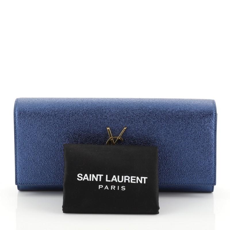 This Saint Laurent Classic Monogram Clutch Metallic Calfskin Long, crafted in blue metallic calfskin leather, features YSL logo at the front and gold-tone hardware. Its magnetic snap closure opens to a black suede interior with slip pocket.