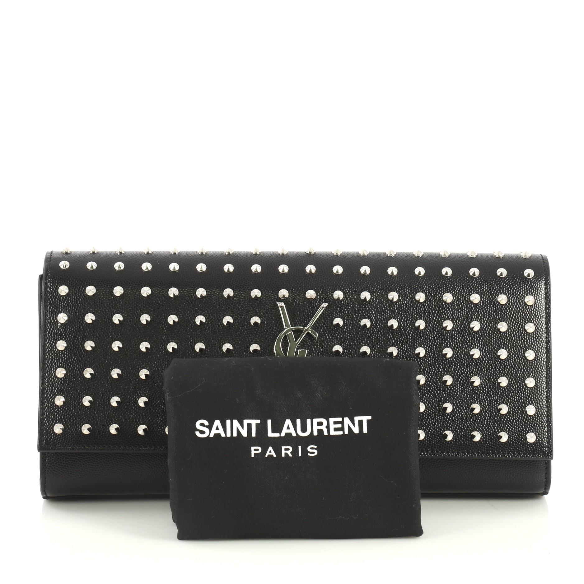 This Saint Laurent Classic Monogram Clutch Studded Leather Long, crafted in black studded leather, features YSL logo at the front and silver-tone hardware. Its magnetic snap closure opens to a black fabric interior with slip pocket. 

Estimated