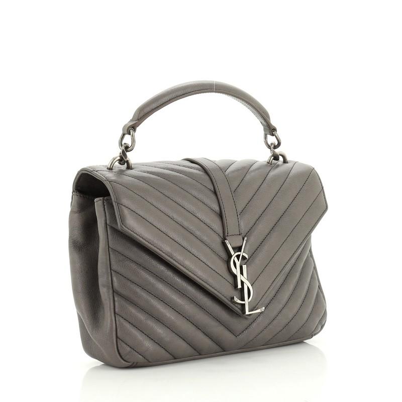 This Saint Laurent Classic Monogram College Bag Matelasse Chevron Leather Medium, crafted in gray matelasse chevron leather, features a single top handle, exterior back pocket, and aged silver-tone hardware. Its magnetic snap closure opens to a