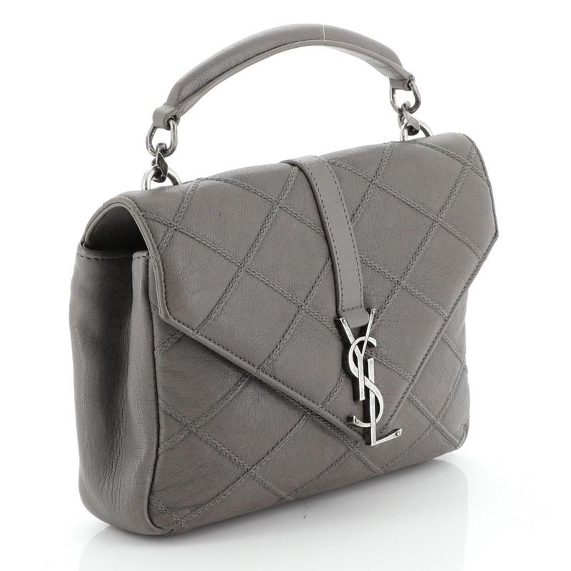 This Saint Laurent Classic Monogram College Bag Quilted Leather Medium, crafted in gray quilted leather, features a single top handle, exterior back pocket, YSL metal logo at the front, and aged silver-tone hardware. Its magnetic snap closure opens