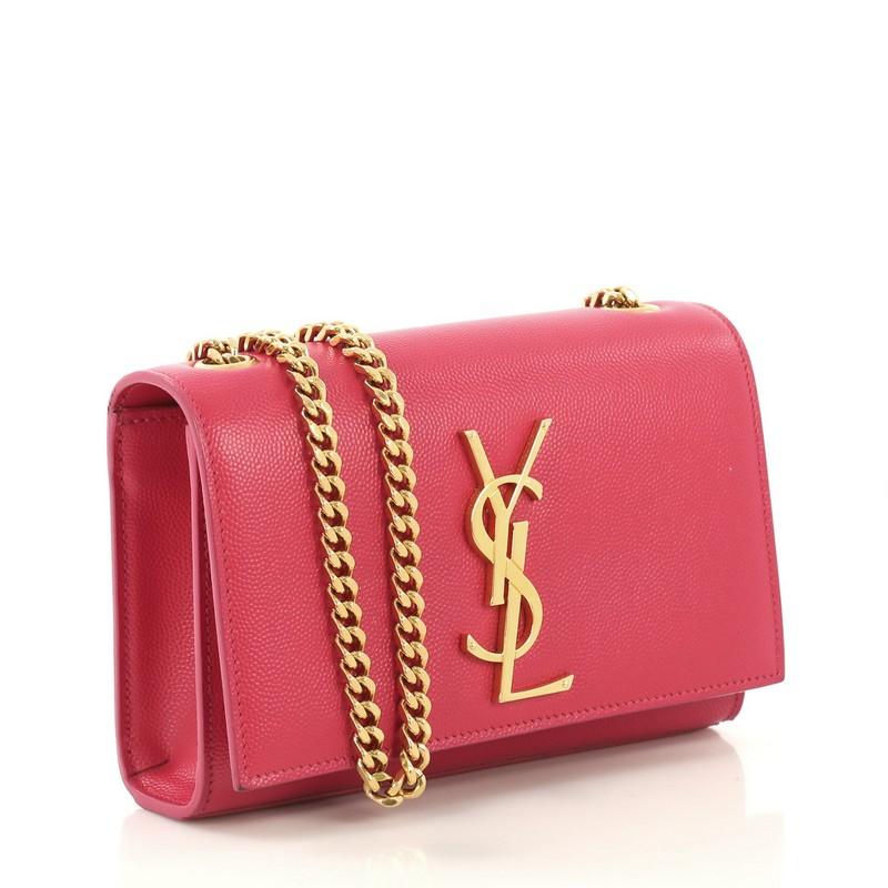 This Saint Laurent Classic Monogram Crossbody Bag Grainy Leather Small, crafted in pink grainy leather, features gourmette chain strap, interlocking YSL logo at its center, and gold-tone hardware. Its magnetic snap closure opens to a black fabric