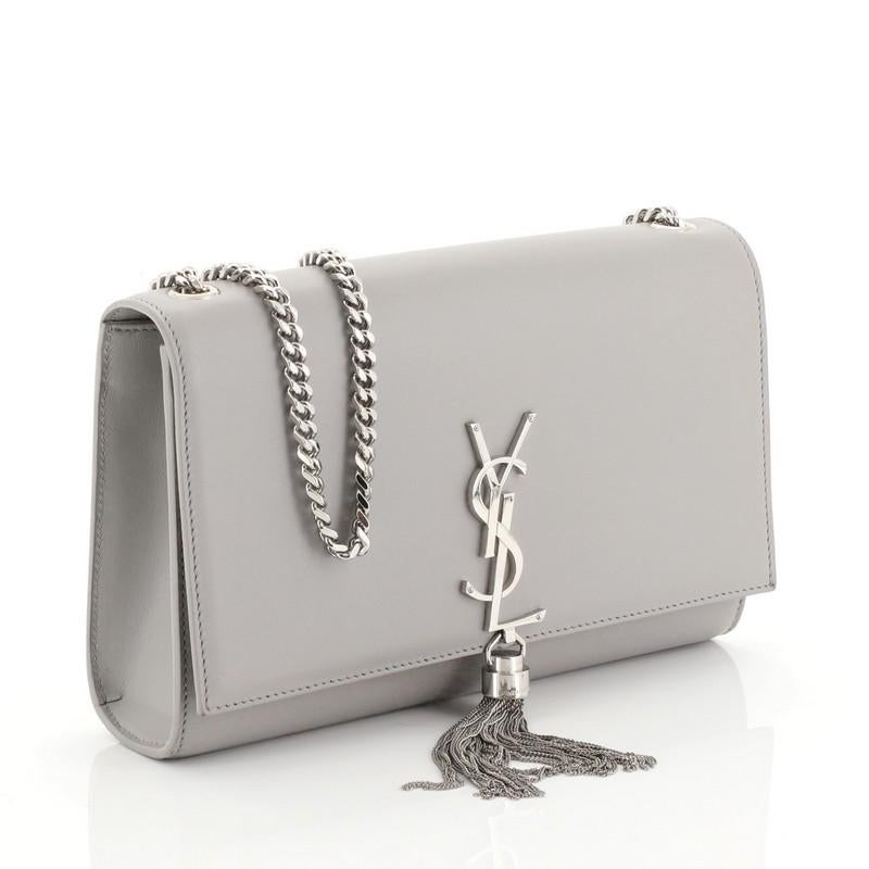 This Saint Laurent Classic Monogram Tassel Crossbody Bag Leather Medium, crafted from gray leather, features gourmette chain strap, interlocking YSL logo at its center with attached fringe tassel, and silver-tone hardware. Its hidden magnetic snap
