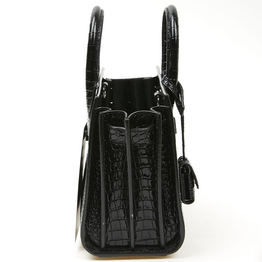 SAINT LAURENT Classic Sac de jour, modello Nano. Questa borsa è in pelle nera goffrata con coccodrillo. Ha due maniglie superiori.
Puoi indossarla come borsa a mano o come borsa a spalla/crossbody grazie alla tracolla rimovibile e regolabile.
C'è