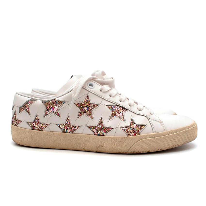 Saint Laurent Court Classic White Star Trainers

- Cut out star detailing on the sides of the shoes with multi-coloured glitter
- Top stitching panel design on the body
- Almond toe shape
- Creamy yellow textured rubber sole
- White laced