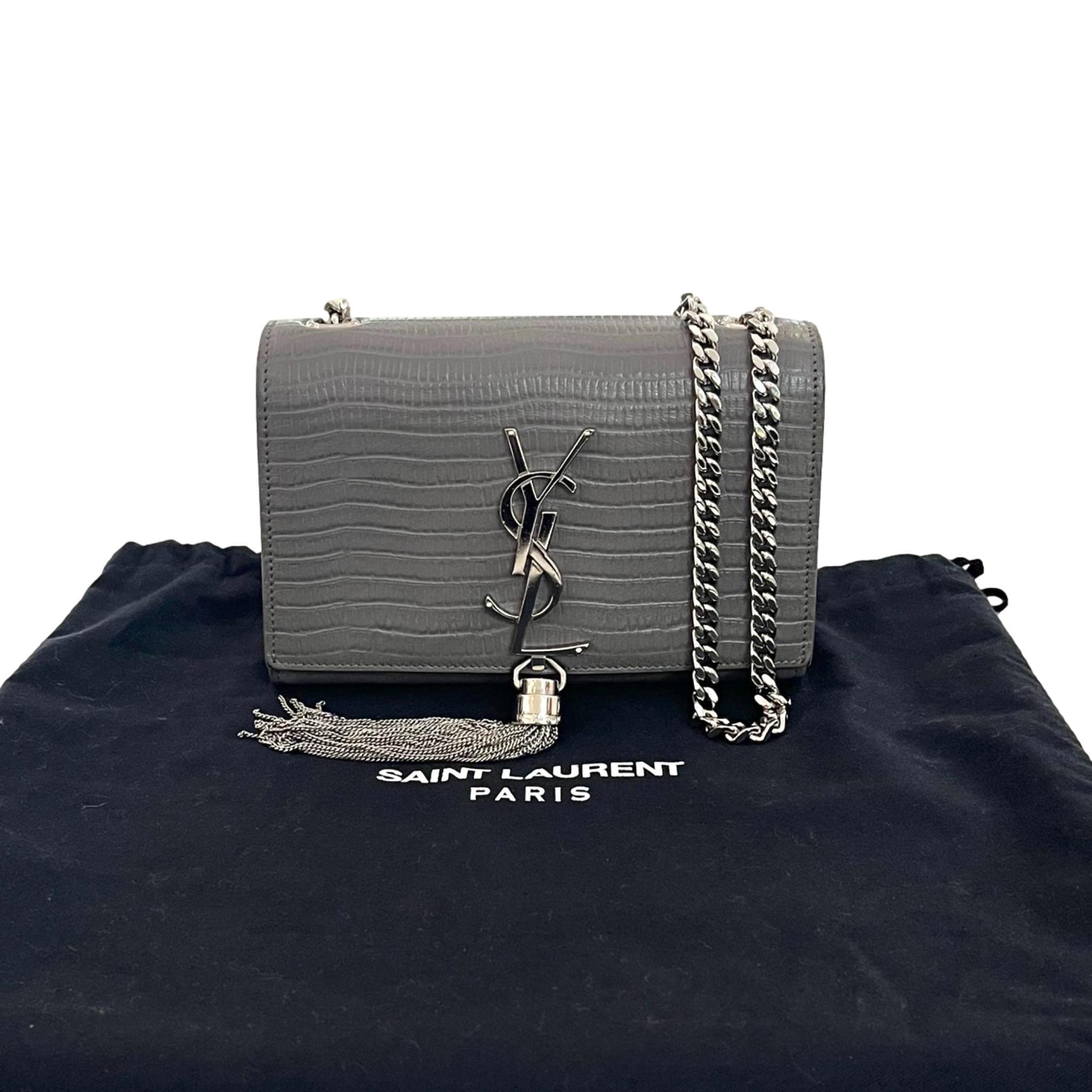 Saint Laurent Croc Embossed Leather Kate Tassel Shoulder Bag

Grey bag crafted in croc embossed calf leather.

Featuring silver 'YSL' logo to the centre with branded chain tassel.

Featuring silver chain shoulder strap and front flap with magnetic