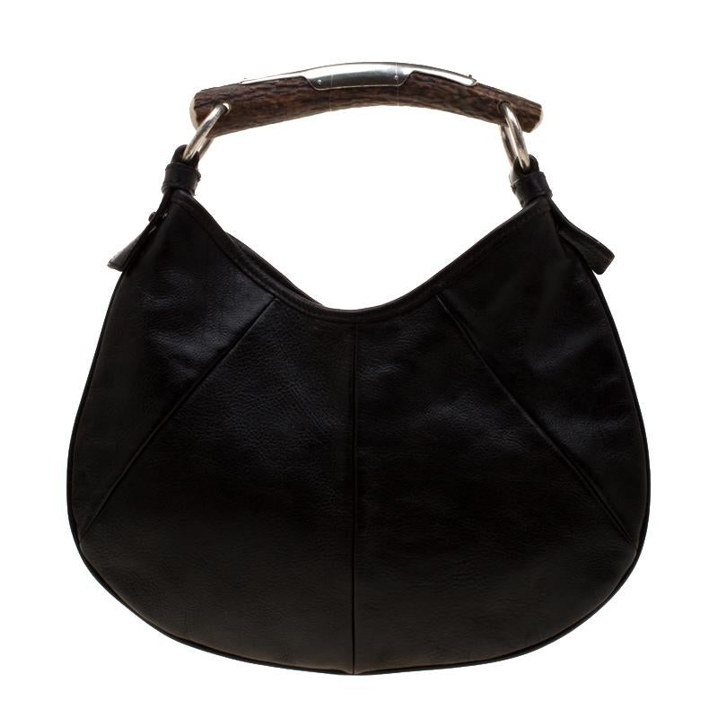 You will love to have this Saint Laurent Paris Mombasa hobo. Crafted from dark brown leather and held by a metal horn-shaped handle, it is a beauty. Fastened by a snap magnetic button, the interior is lined with fabric to house your essentials with