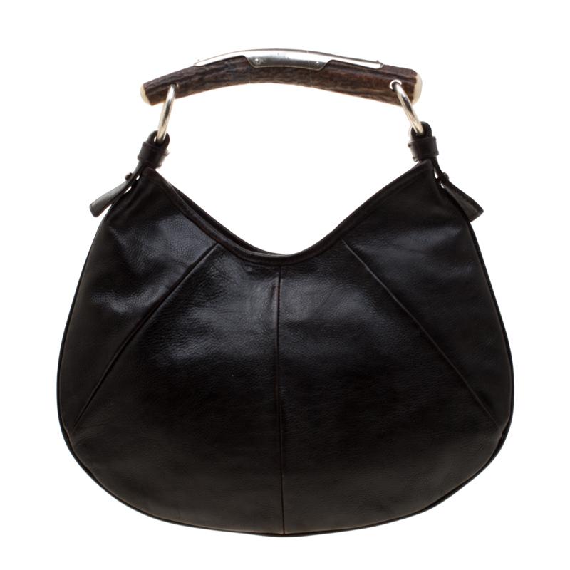 You will love to have this Saint Laurent Paris Mombasa hobo. Crafted from dark brown leather and held by a metal horn-shaped handle, it is a beauty. Fastened by a snap magnetic button, the interior is lined with fabric to house your essentials with