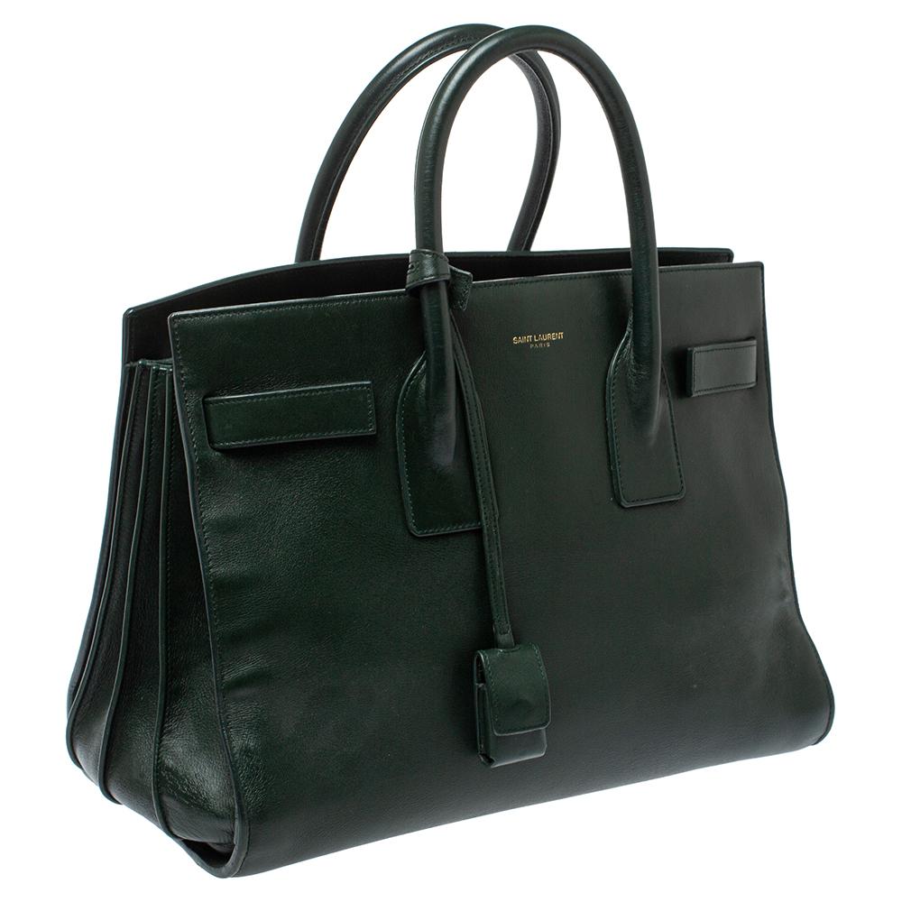 This Sac de Jour tote by Saint Laurent has a structure that simply spells sophistication. Crafted from dark green leather, the bag is held by double top handles. The tote comes with a suede-lined interior with enough space to store your necessities