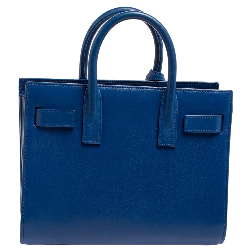 This Sac de Jour tote by Saint Laurent has a structure that simply spells sophistication. Crafted from electric blue leather, the bag is held by double top handles. The tote comes with a suede-lined interior with enough space to store your