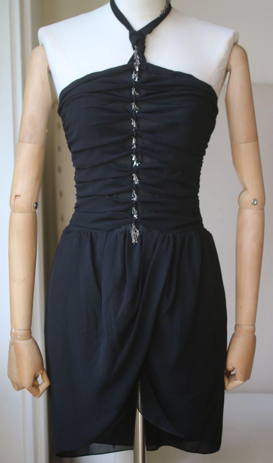 Its drapes picked out by mini metallic embellishments for a seditious finish. The design features a halterneck with a back tie fastening and a twisted detail to the chest. Leaving the back open while the skirt falls to a short length. Accented by a