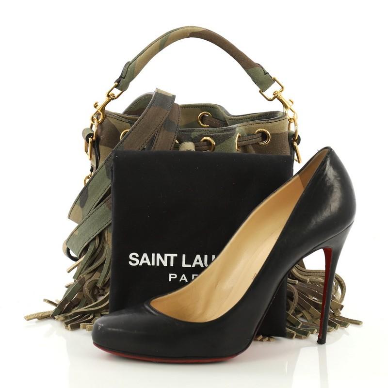 This Saint Laurent Fringe Emmanuelle Bucket Bag Printed Suede Small, crafted in camouflage fringe printed suede, features a detachable looped handle, adjustable suede strap, protective base studs, side zip pockets, and gold-tone hardware. Its