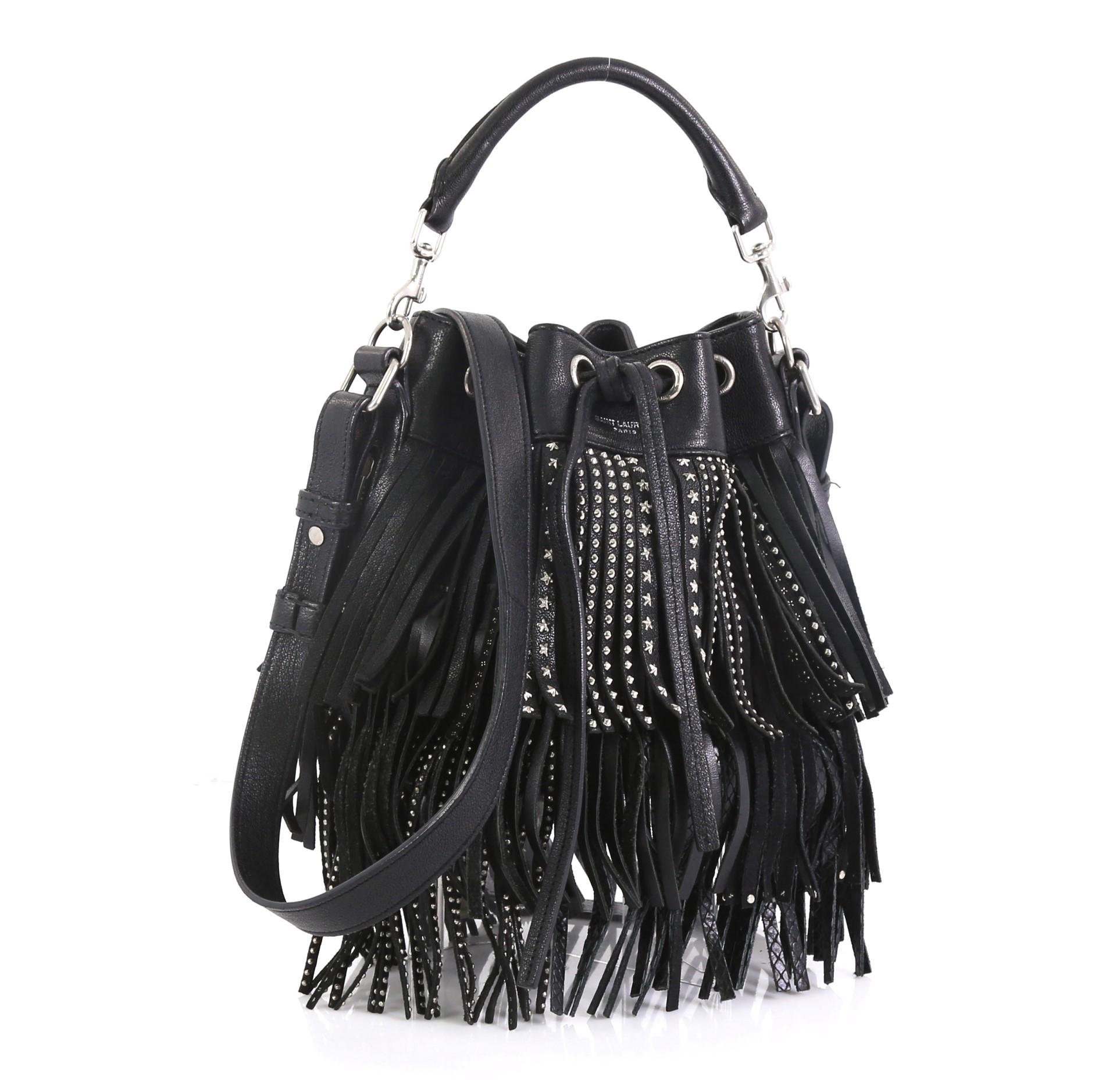 This Saint Laurent Fringe Emmanuelle Bucket Bag Studded Leather Small, crafted in black studded leather, features a detachable looped handle, adjustable leather strap, side zip pocket, fringe detailing and silver-tone hardware. Its drawstring