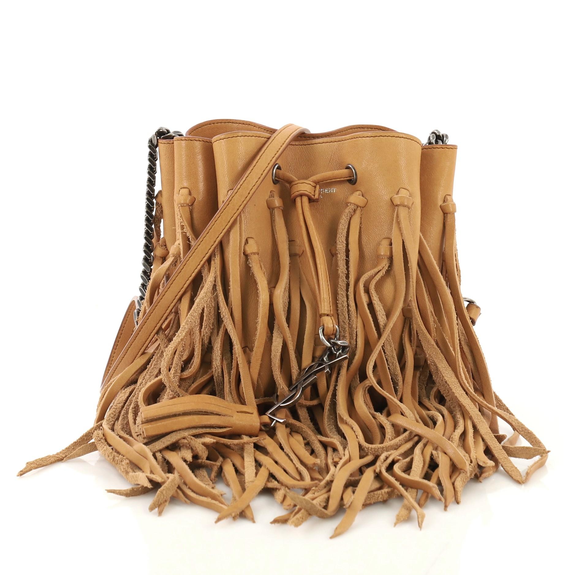 This Saint Laurent Fringe Monogram Bourse Bucket Bag Leather Mini. crafted in brown leather, features a chain and leather crossbody strap, cascading leather fringes, signature YSL logo and aged silver-tone hardware. Its drawstring closure opens to a