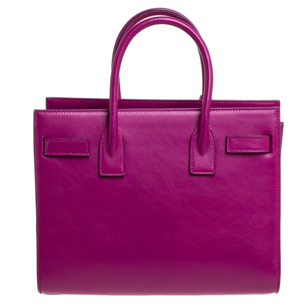 This Sac de Jour tote by Saint Laurent has a structure that simply spells sophistication. Crafted from fuchsia pink Leather, the tote is held by double top handles. It comes with a leather-lined interior with enough space to store your necessities