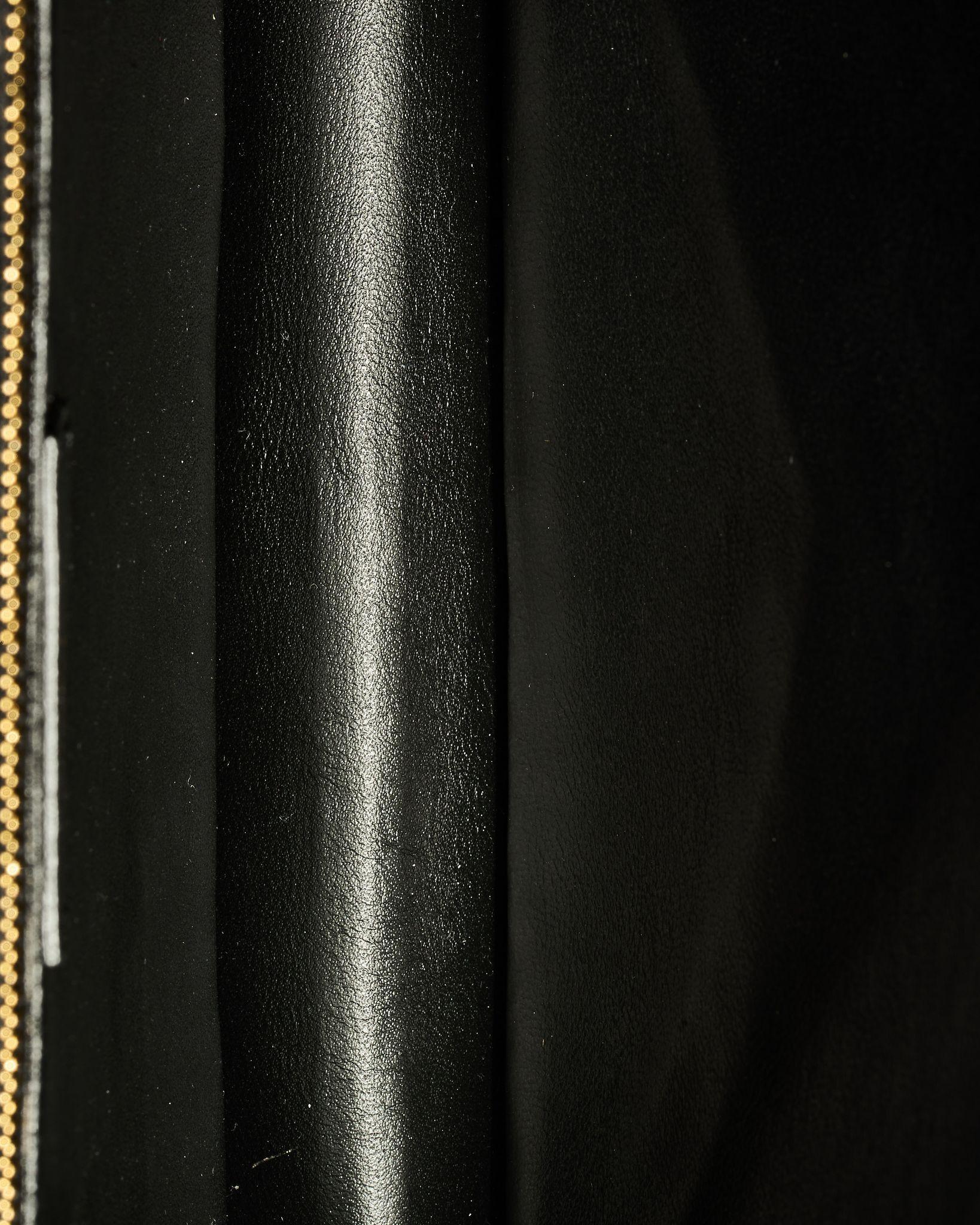 Sac signé Saint Laurent, modèle Gaby en taille Medium, en satin noir avec bordures et ferrures dorées. Le rabat avant est orné du classique logo 