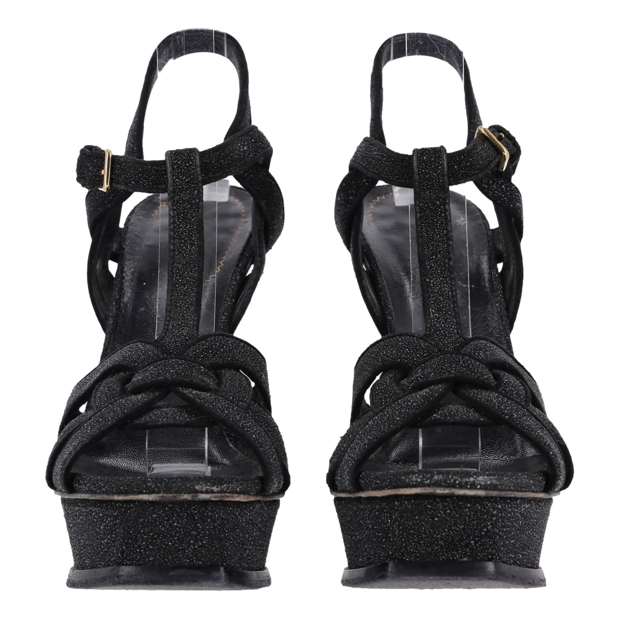 Saint Laurent Glitter Calfskin Tribute Platform Sandals

Black platform sandals crafted from calfskin leather fully covered with sparkling glitter.

Intertwining straps to the vamp, slingback design with buckled ankle closure and high stiletto