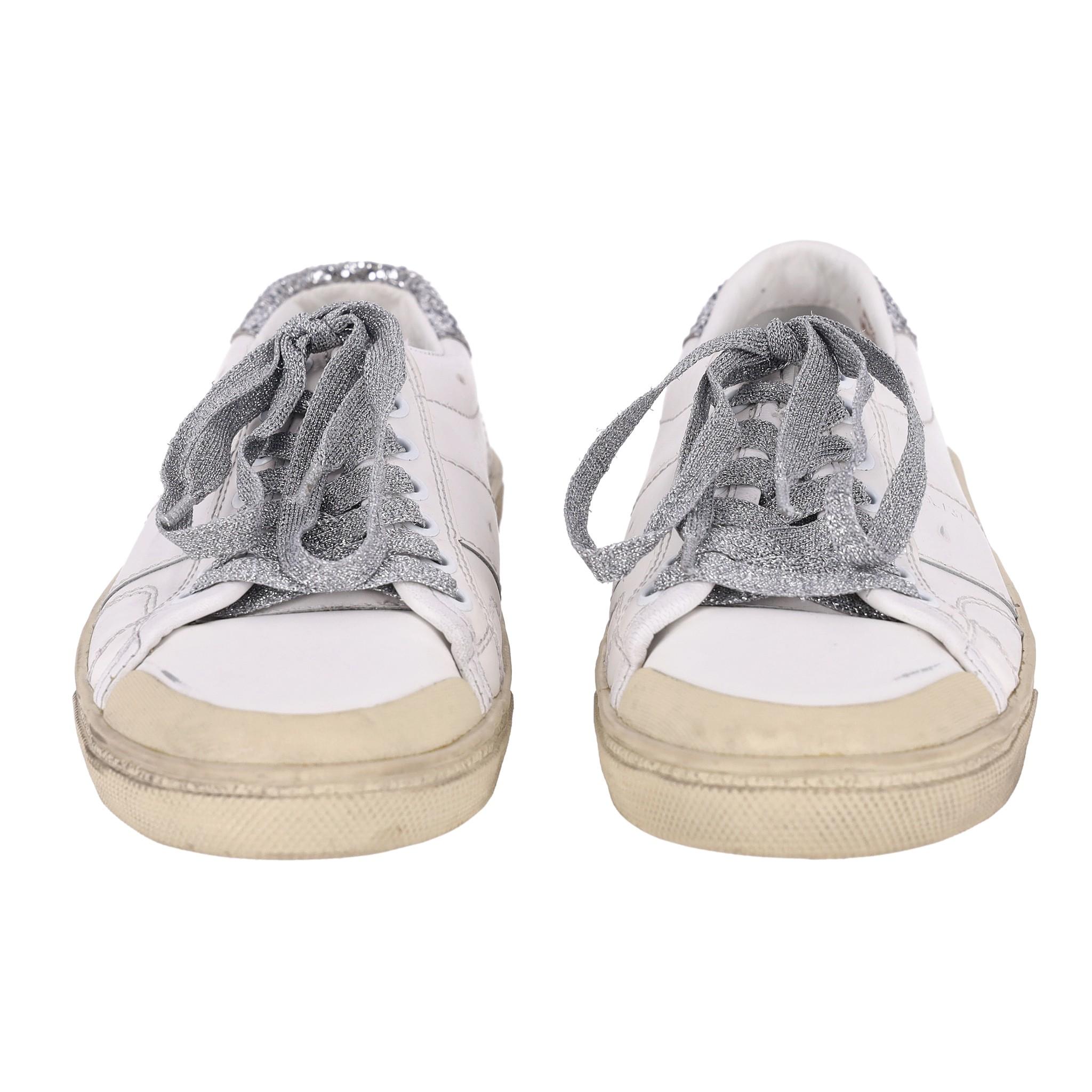 Saint Laurent Glitter Detailed Leather Sneakers

White SL/37 sneakers crafted from leather and styled with distressed design.

Detailed with silver glitter laces and accent to the heel.

Featuring beige rubber soles, round toe and leather