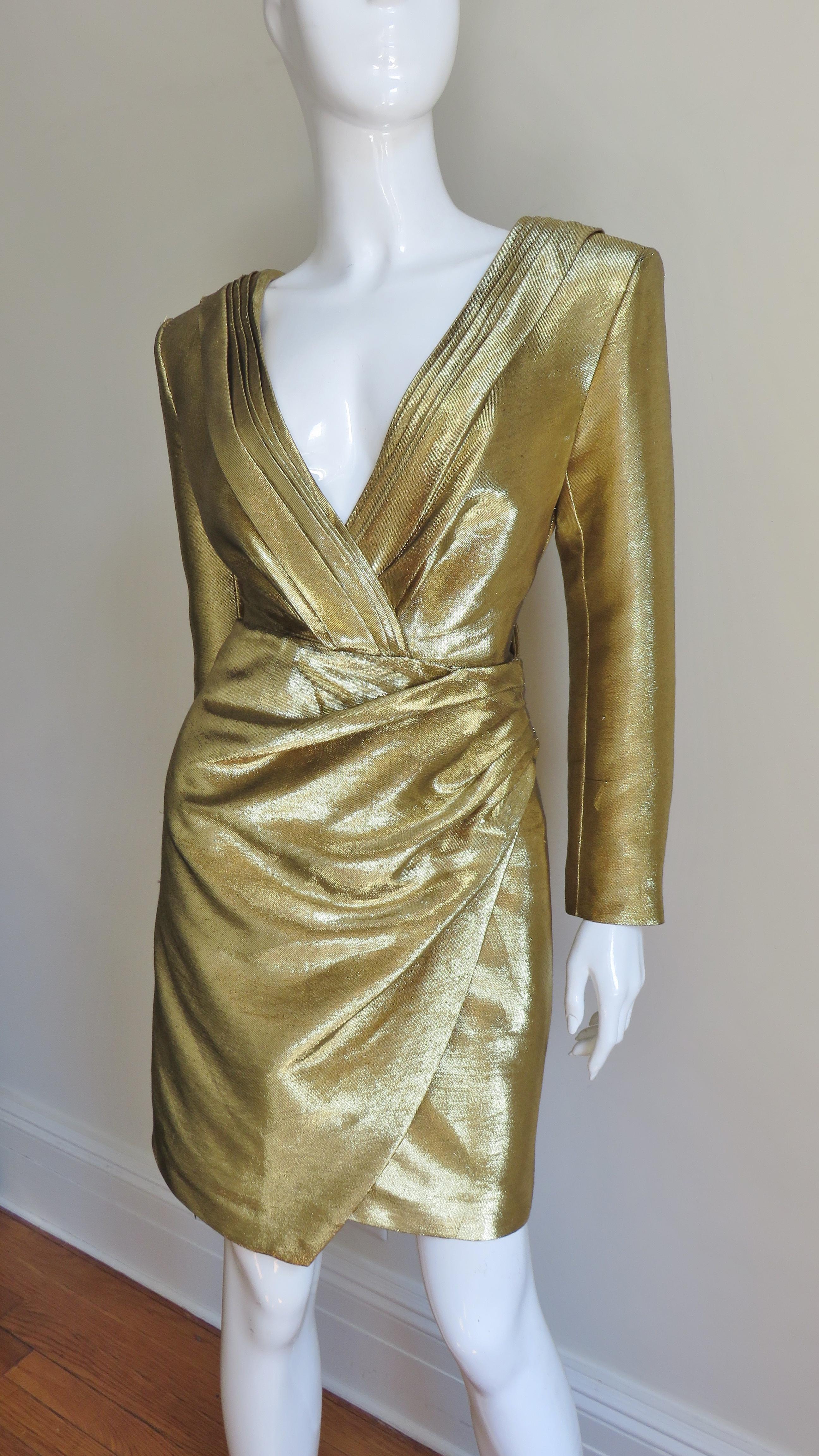 An incredible gold lame dress from Saint Laurent worn on runways and magazine covers. It has a wrapping V front and back neckline and a draping front panel skirt. There are small shoulder pads, 5 self covered buttons on each cuff and a matching gold