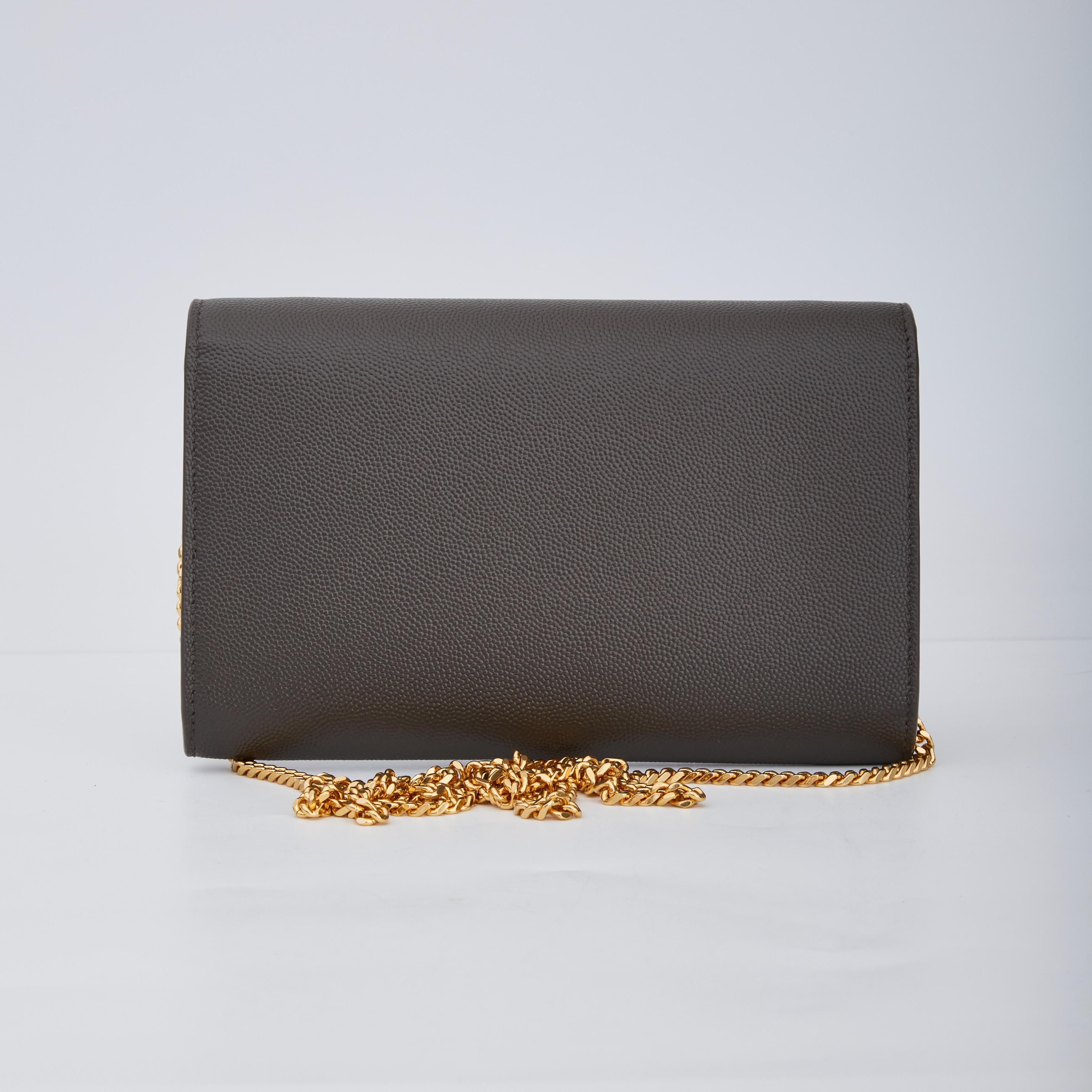This Saint Laurent envelope flap Bag is from 2020 and is made with Grain De Poudre calfskin leather in anthracite grey. The bag features a fold over front envelope flap, shiny gold tone hardware, the signature YSL logo plaque and a chain-link