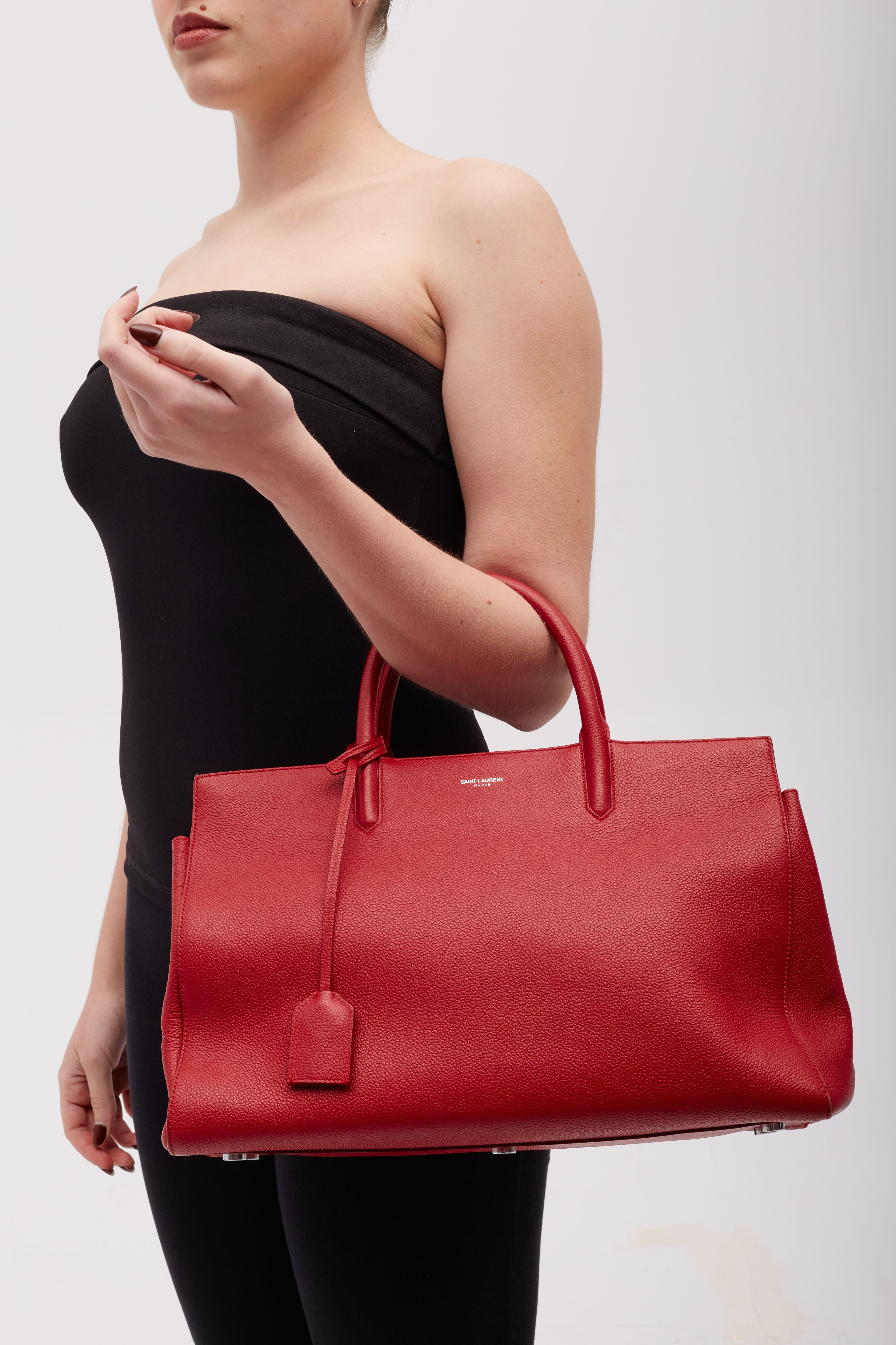 This tote bade is made of red grained calfskin leather in red. The bag features dual rolled leather top handles, optional shoulder strap and silver hardware. The top zipper opens to a red suede interior with zipper and patch pockets.

Color: