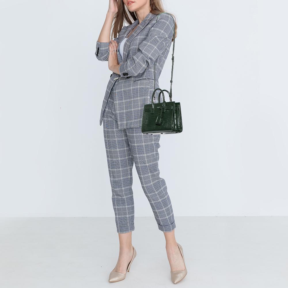 This Sac de Jour tote by Saint Laurent has a structure that simply spells sophistication. Crafted from green croc-embossed leather, the bag is held by double top handles. The tote comes with a leather-lined interior with enough space to store your