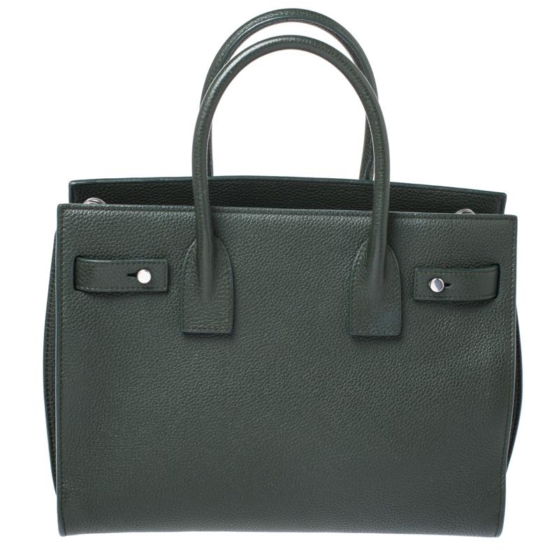 This Sac de Jour tote by Saint Laurent has a structure that simply spells sophistication. Crafted in Italy, it is made from green leather. The bag is held by double top handles and a single shoulder strap. The tote comes with a fabric-lined interior