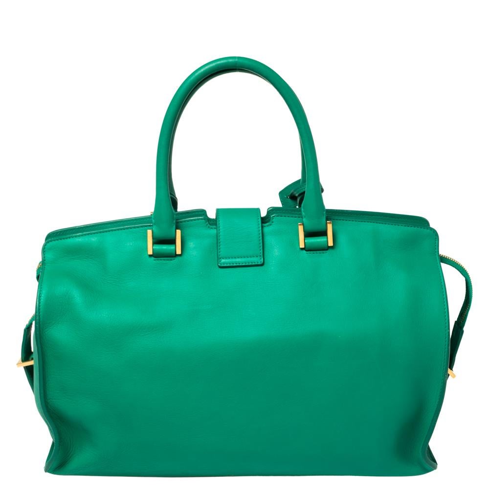 This elegant green-hued Cabas Ligne Y tote bag from Saint Laurent is ideal for everyday use. Crafted from quality leather, the bag is detailed with a gold-tone Y motif snap closure, dual handles, and protective metal feet at the bottom. The top zip