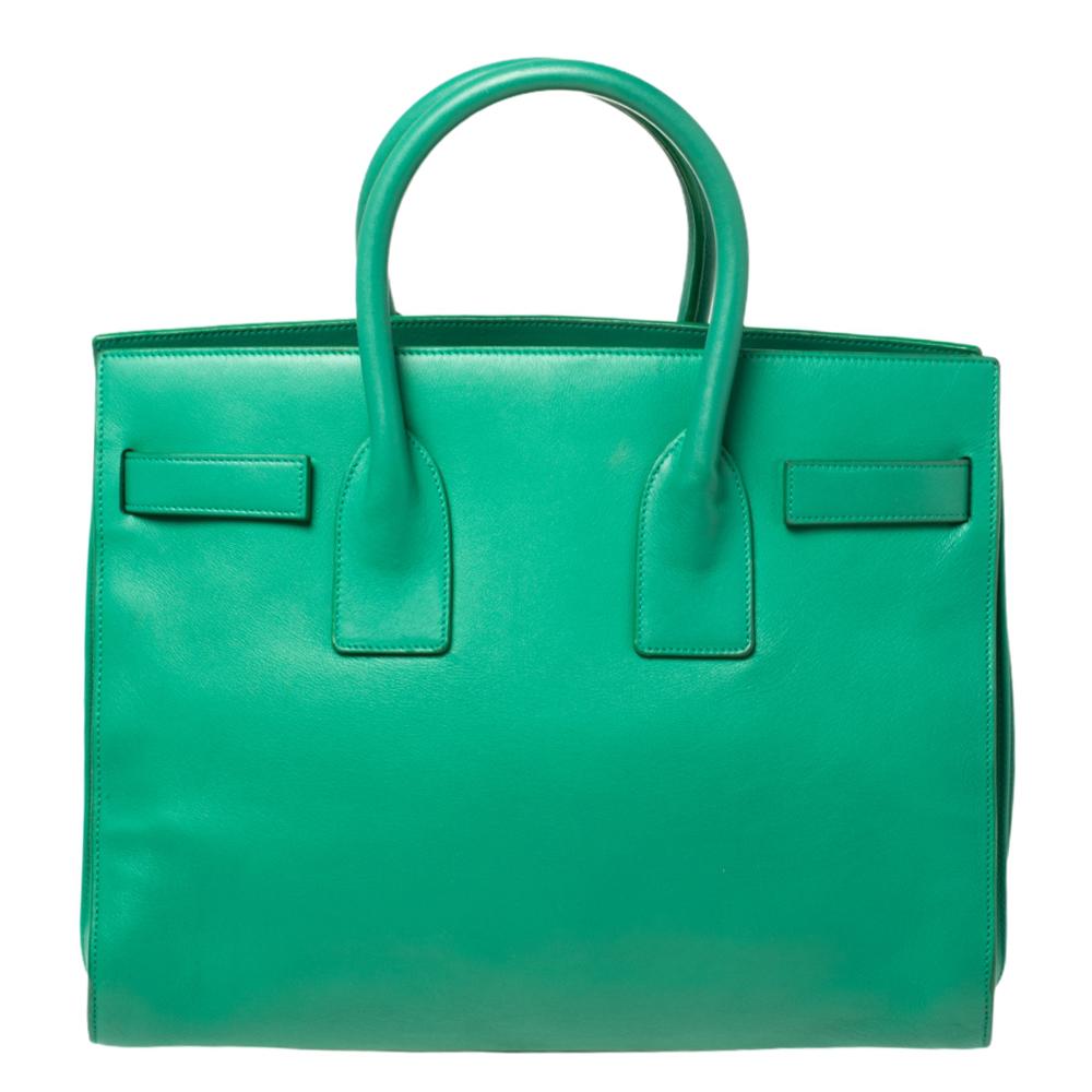 This Sac de Jour tote by Saint Laurent has a structure that simply spells sophistication. Crafted from green leather, the bag is held by double top handles. The tote comes with a suede-lined interior with enough space to store your necessities and