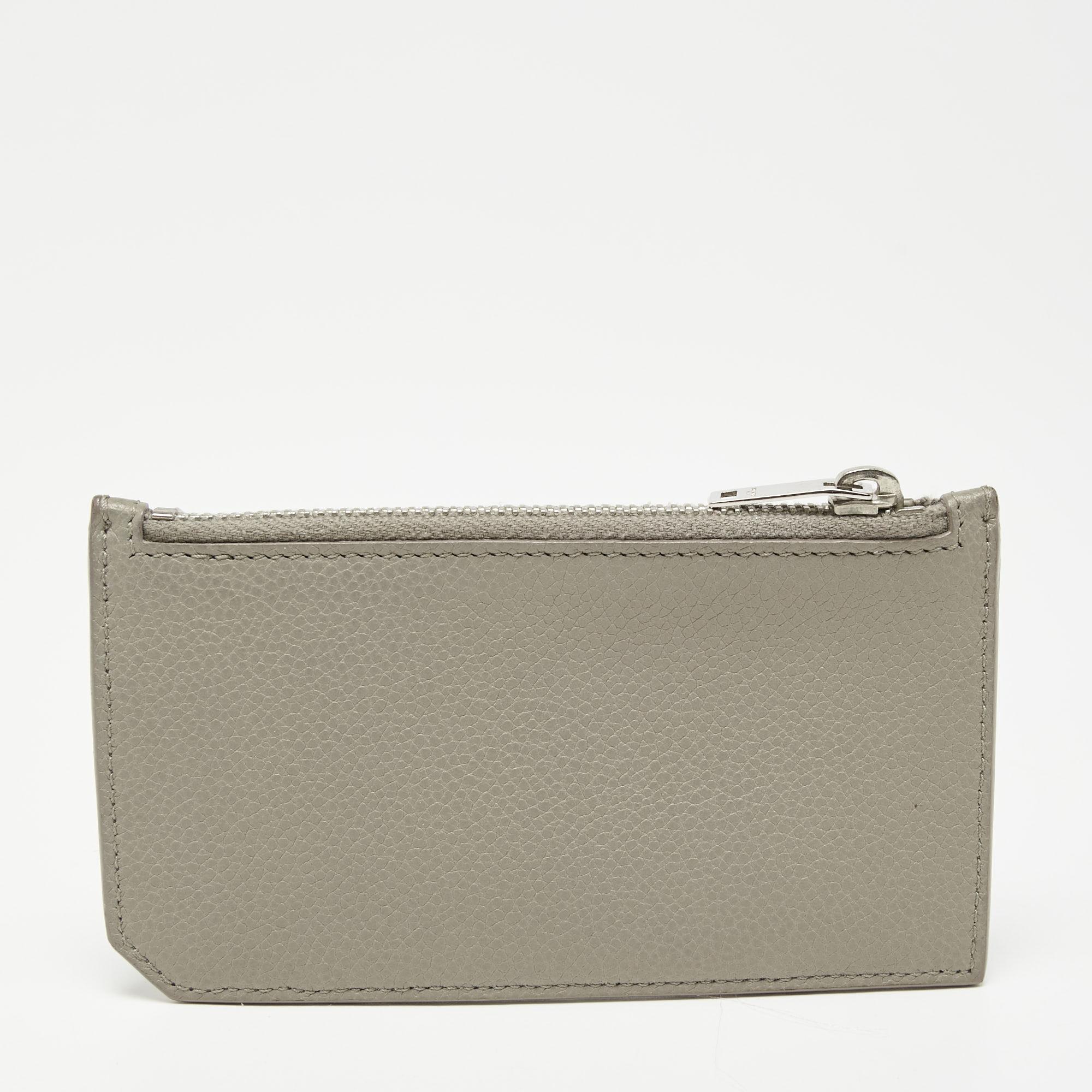 The grey exterior of this Saint Laurent card case is divided into different slots making it a practical choice. Created from leather, it flaunts a brand signature on the front, a lined interior, and a top zipper closure.

Includes: Original Dustbag