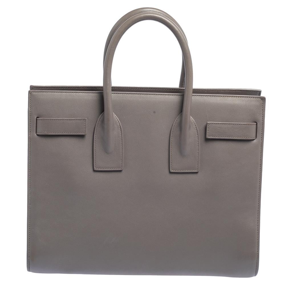 This Sac de Jour tote by Saint Laurent has a structure that simply spells sophistication. Crafted from grey leather, the bag is held by double top handles. The tote comes with a suede-lined interior with enough space to store your necessities and
