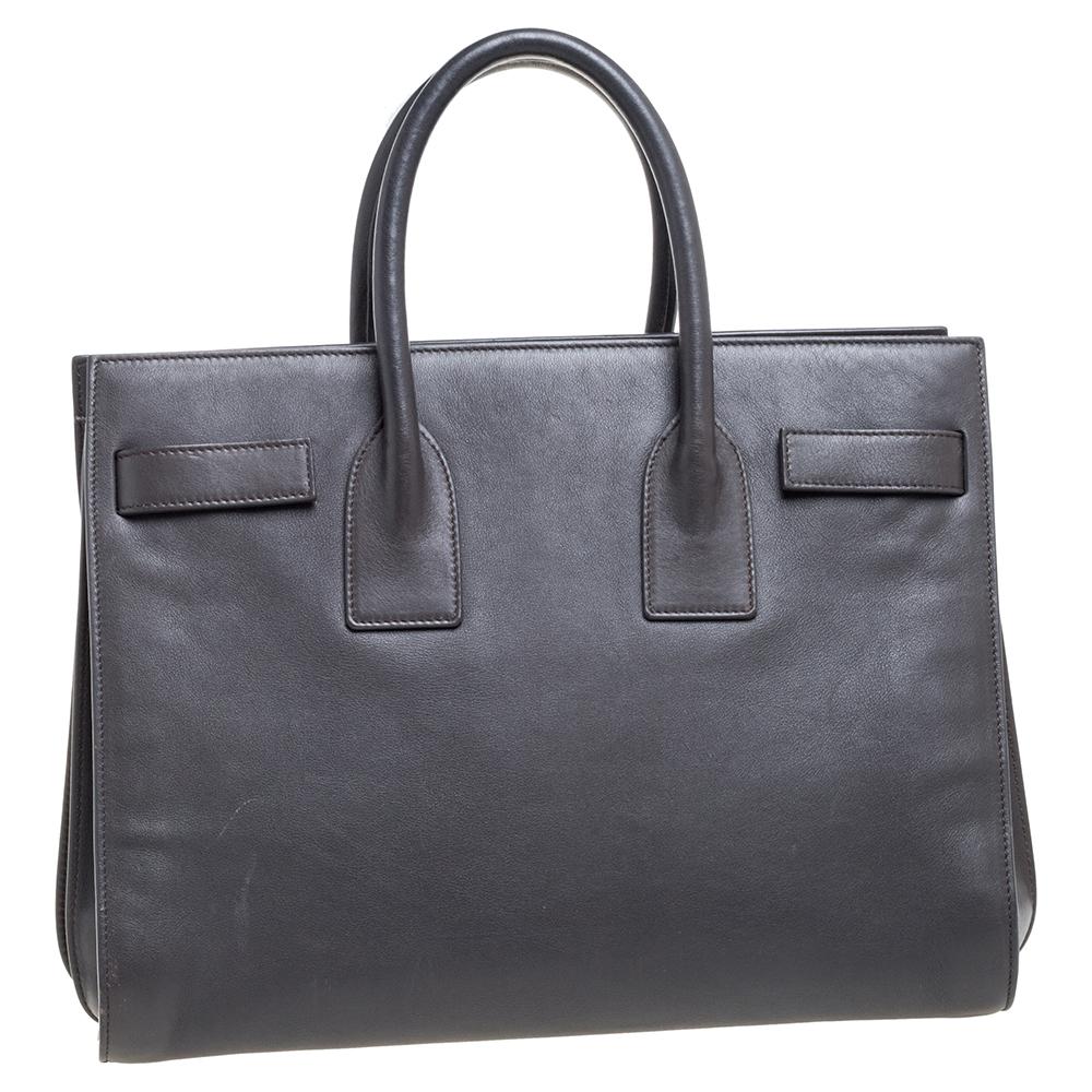 This Sac de Jour tote by Saint Laurent has a structure that simply spells sophistication. Crafted from grey-hued leather, the bag is held by double top handles. The tote comes with a suede-lined interior with enough space to store your necessities