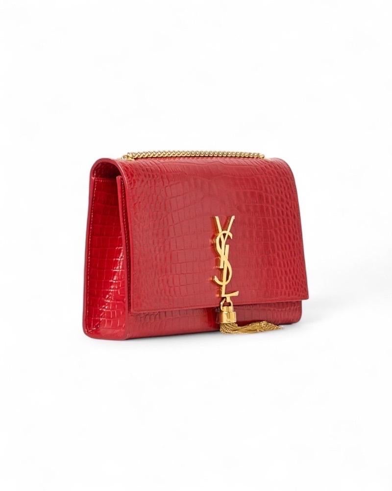 Borsa firmata Saint Laurent, modello Kate nella misura media, realizzata in pelle cocco rossa con hardware dorato. Dotata di una patta con il classico logo del marchio 