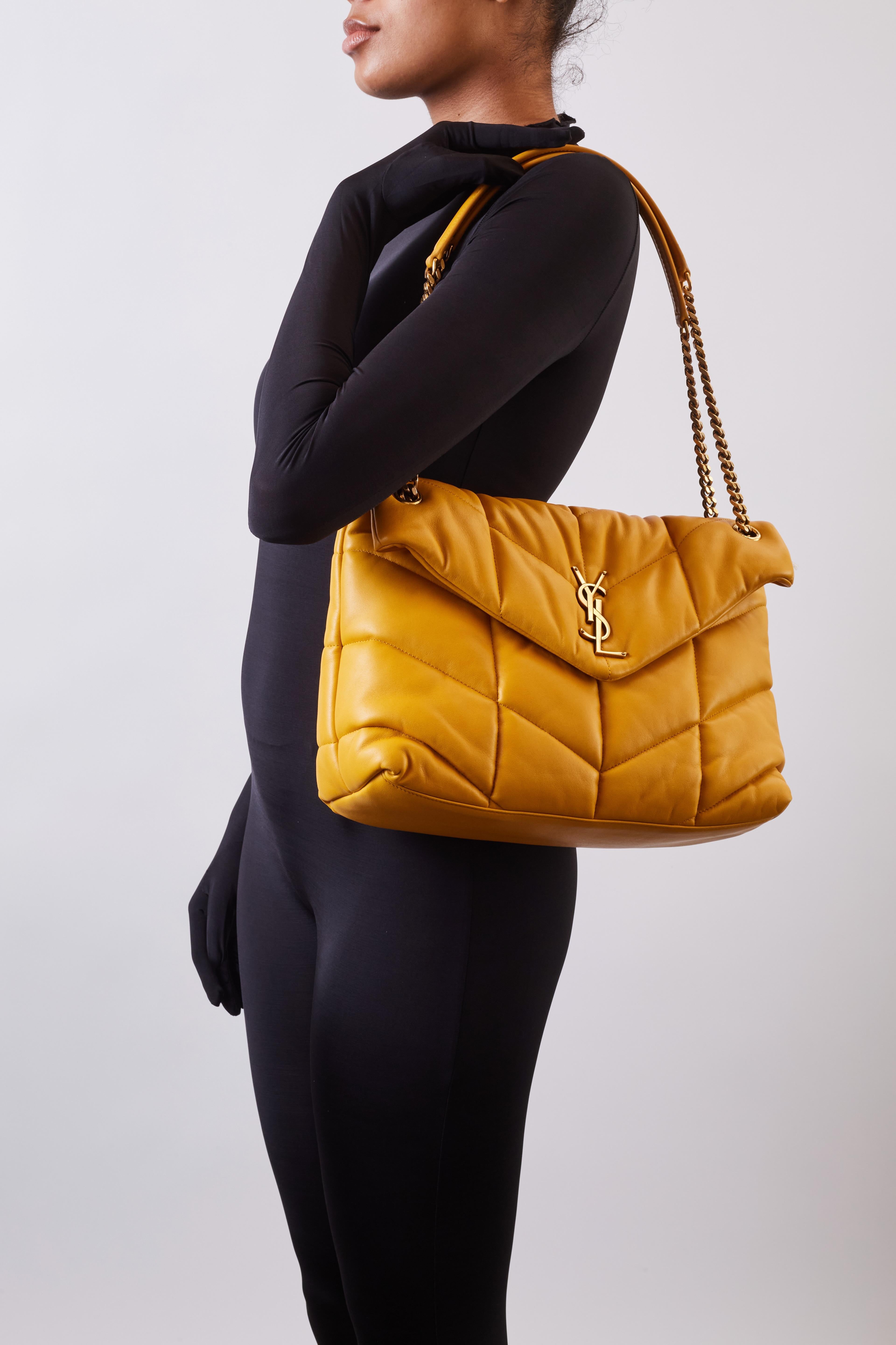 This famous style Saint Laurent bag is called the Loulou puffer shoulder bag and this is size medium. The bag is made with soft and supple lambskin leather in dark yellow/saffran and features a sliding curb chain shoulder strap, leather strap pads,