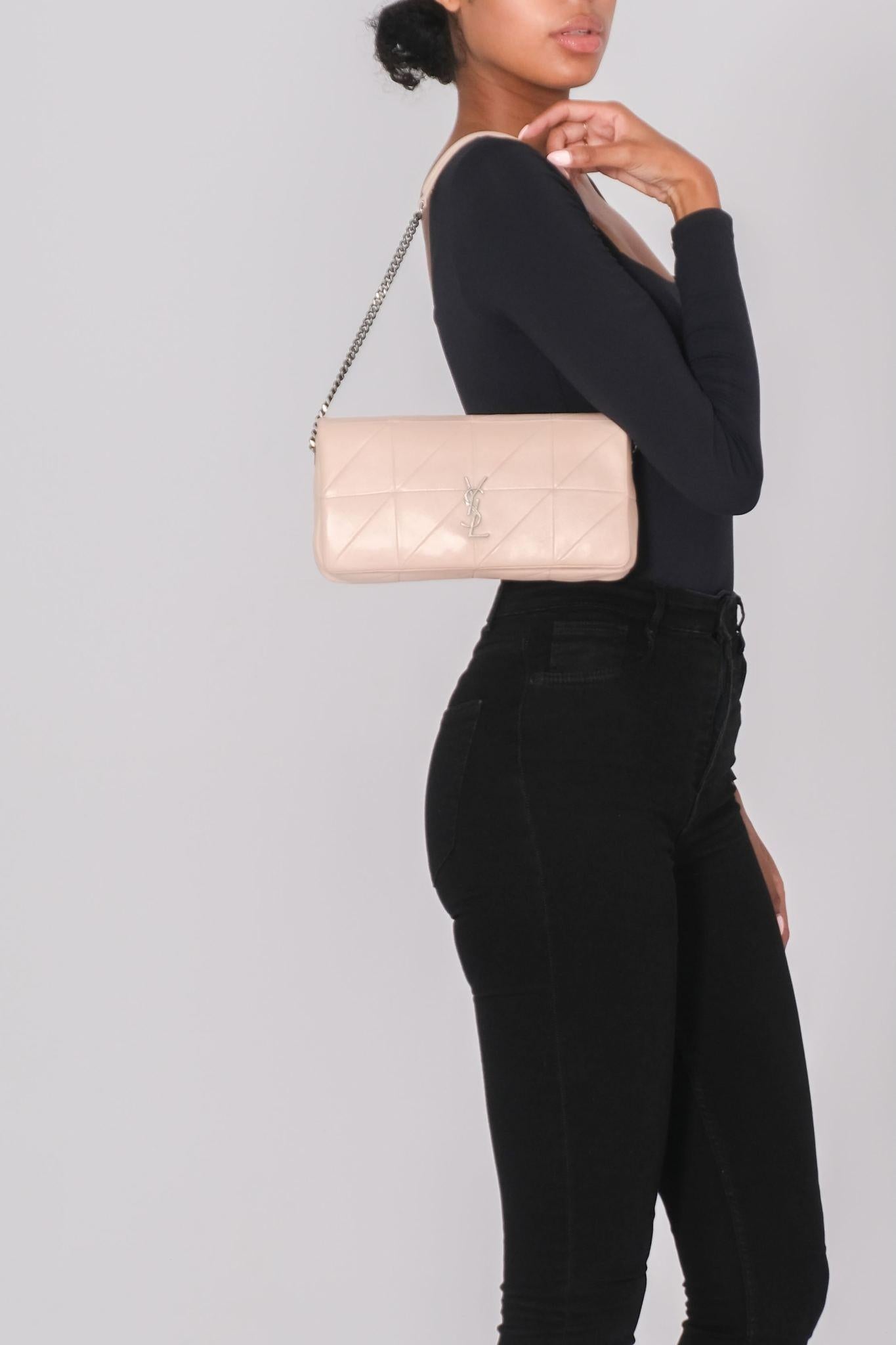 This shoulder bag is made of lambskin leather in pink nude. The bag features an aged ruthenium bijoux chain link cross body shoulder strap with shoulder pads and a facing flap with a matching aged YSL logo. The flap opens to a black fabric interior