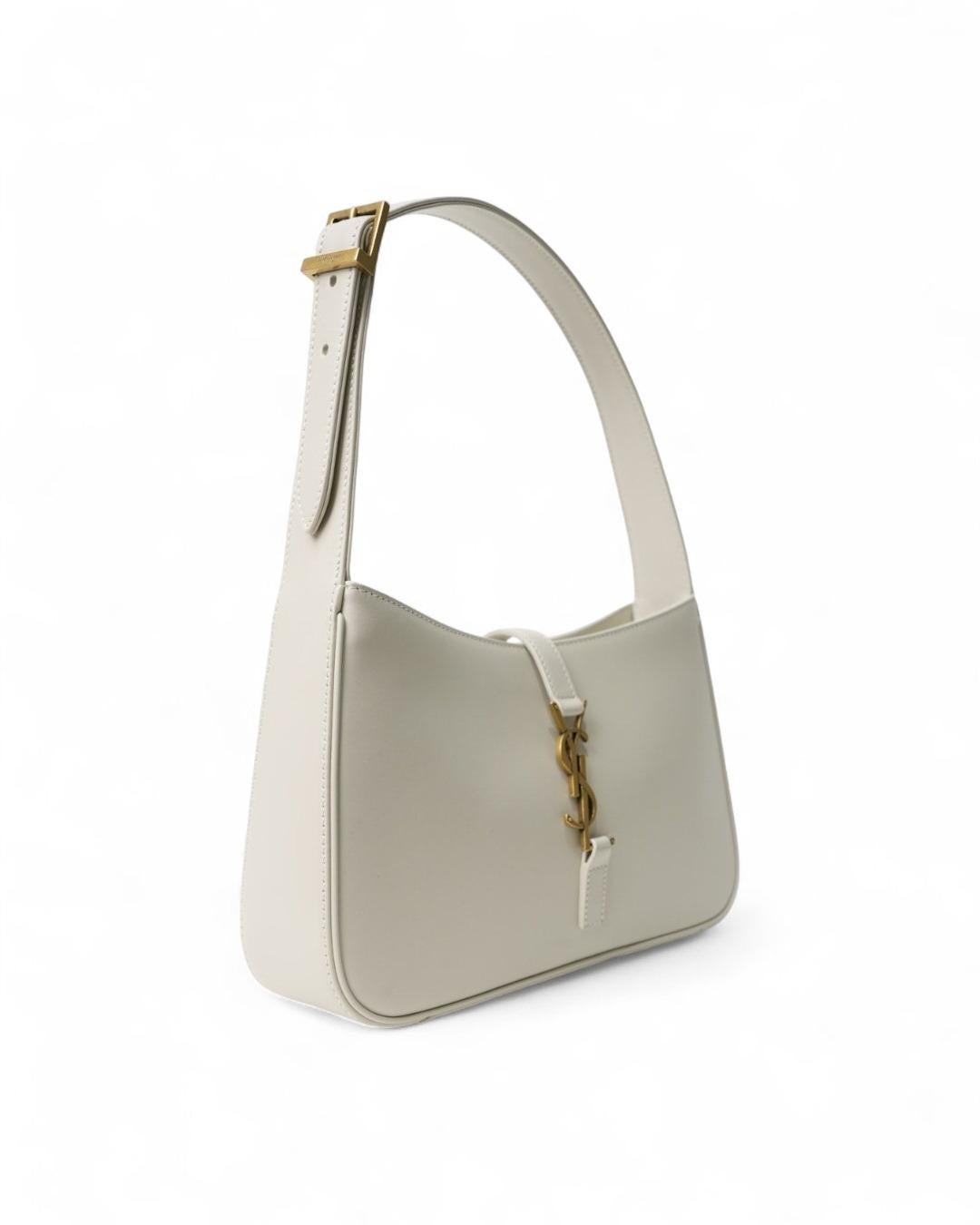 Sac signé Saint Laurent, modèle Le 5 à 7 Hobo, en cuir lisse de couleur blanche et ferrures dorées. Doté d'un fermoir à emboîtement avec le logo YSL en métal classique de la marque, doublé intérieurement en daim beige et doté d'une poche zippée