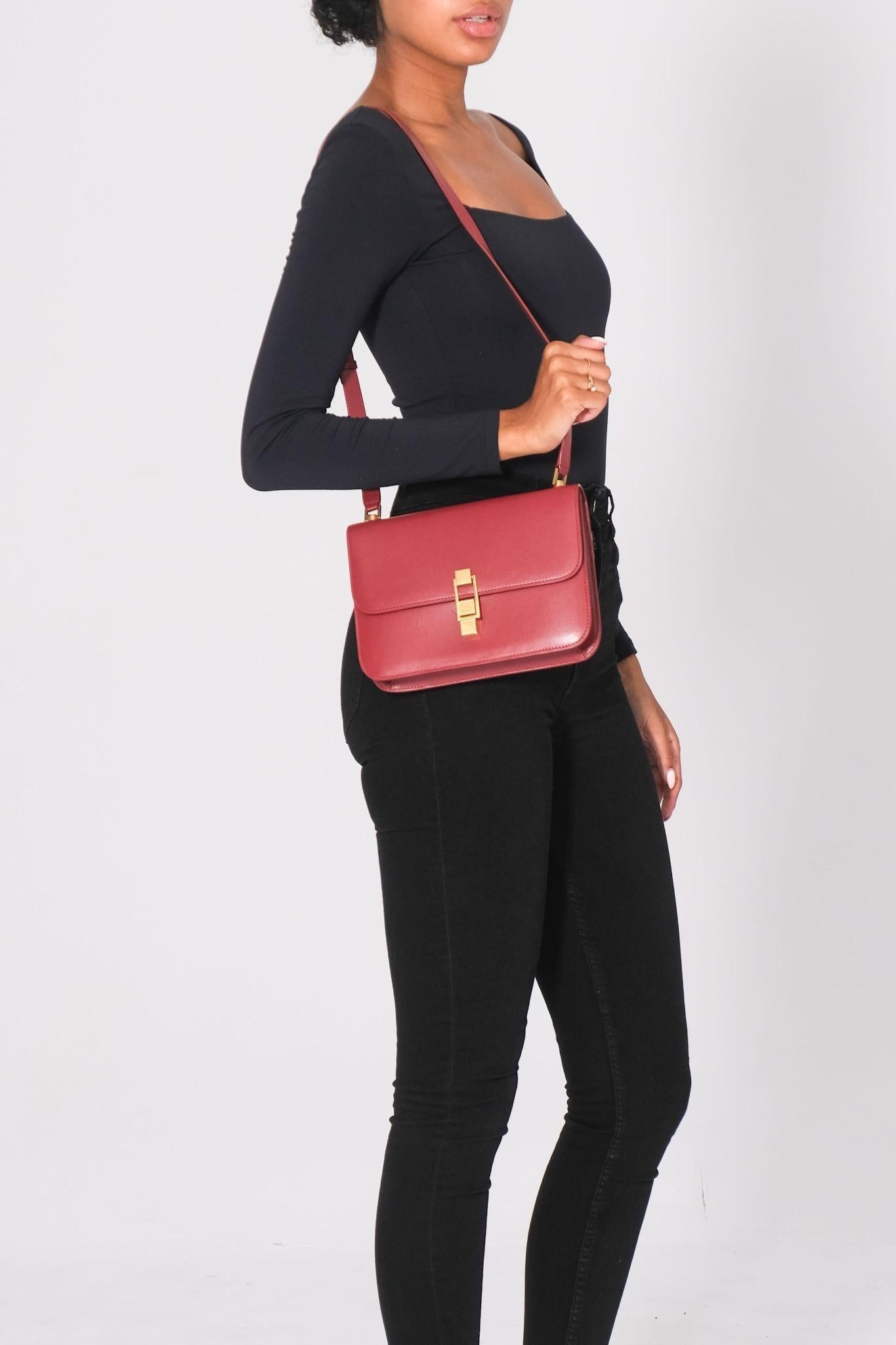 This messenger bag is made of smooth calfskin leather in red. The bag features an adjustable leather crossbody strap with gold links and a flap with a gold Saint Laurent engraved press lock. The flap opens to reveal a flat exterior pocket and a