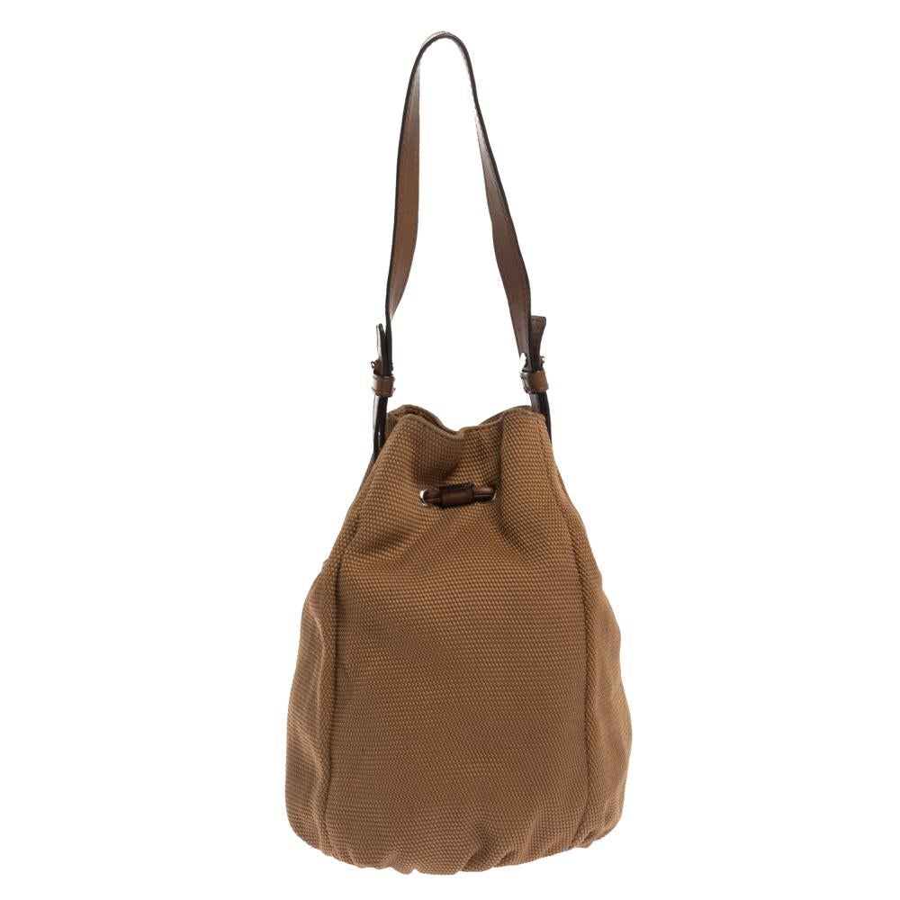 Saint Laurent is known for its quality craftsmanship and designs. This brown bag is crafted from canvas and neatly detailed with an embossed YSL logo on the front. It has a top drawstring closure that opens to a capacious fabric-lined interior,