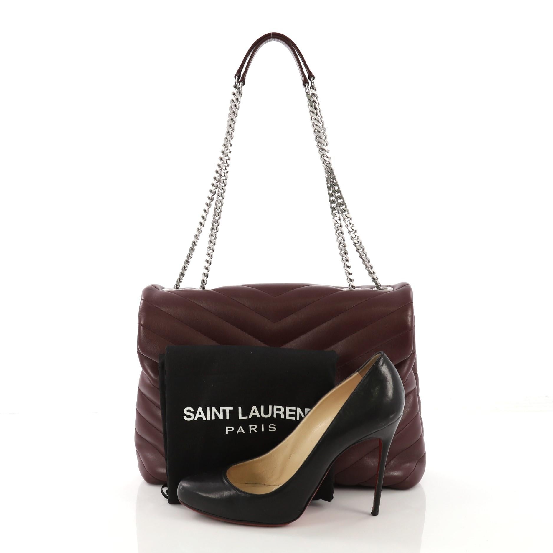 This Saint Laurent LouLou Shoulder Bag Matelasse Chevron Leather Medium, crafted in burgundy matelasse chevron leather, features a chain link strap with leather pad, YSL logo on the front, and silver-tone hardware. Its magnetic snap closure opens to