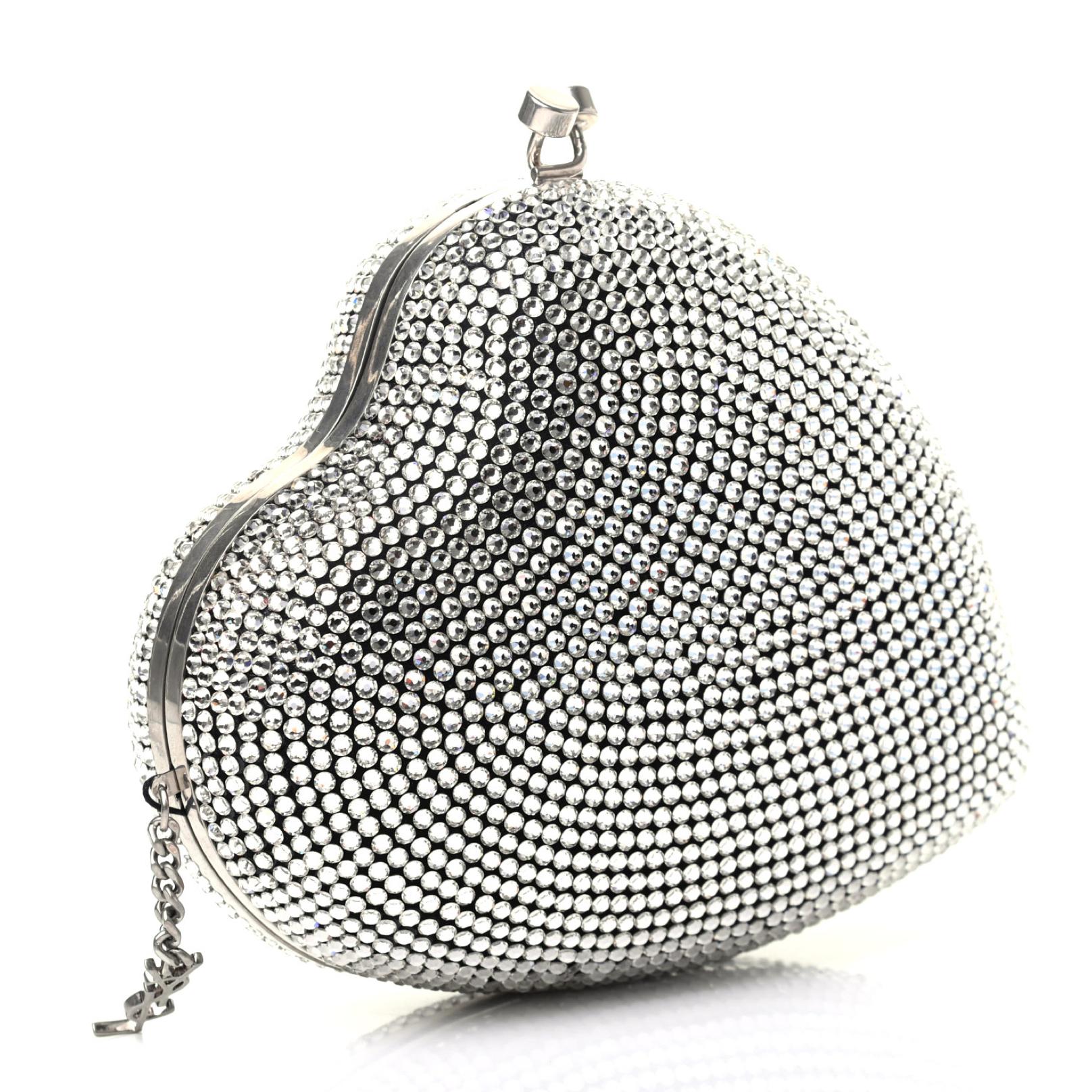 This sculptural heart shape clutch features, an asymmetrical construction, Swarovski crystal detailing, a long silver chain for shoulder carry, kiss-lock fastening and a YSL logo charm at the hinged opening. Limited edition. Can be worn as a clutch