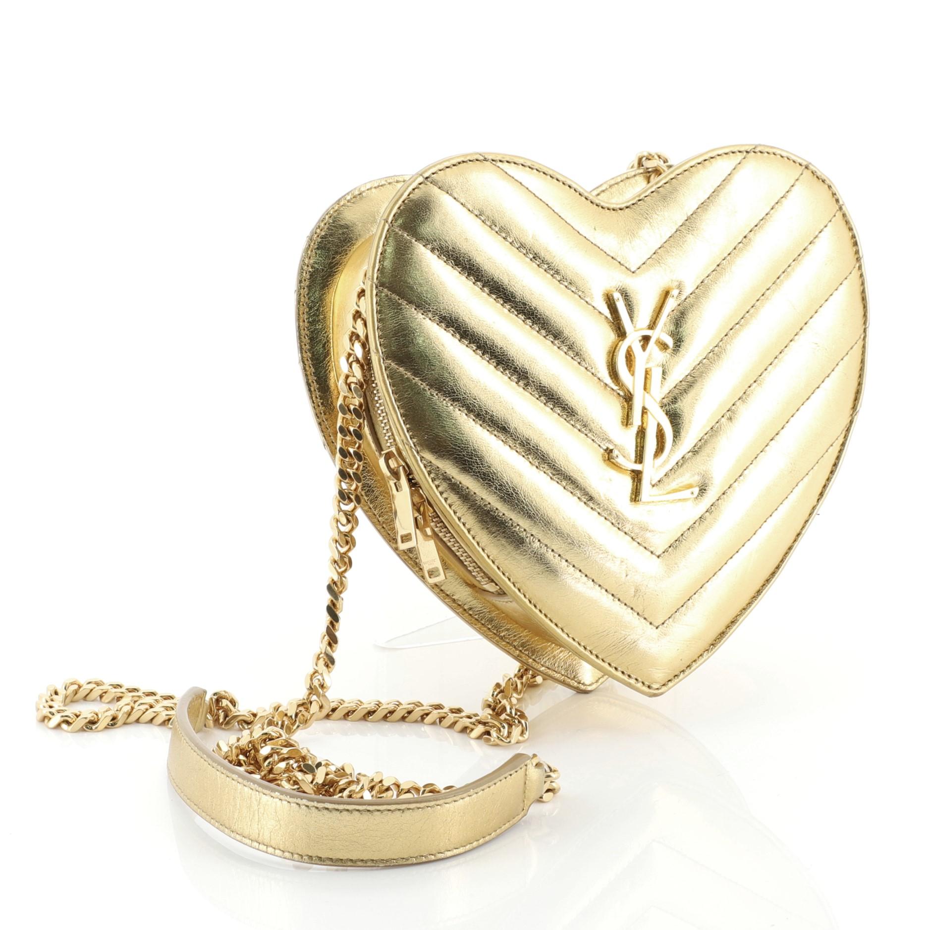 This Saint Laurent Love Heart Chain Bag Matelasse Chevron Leather Small, crafted from gold matelasse chevron leather, features chain link strap with leather shoulder pad, interlocking YSL logo and gold-tone hardware. Its zip closure opens to a black