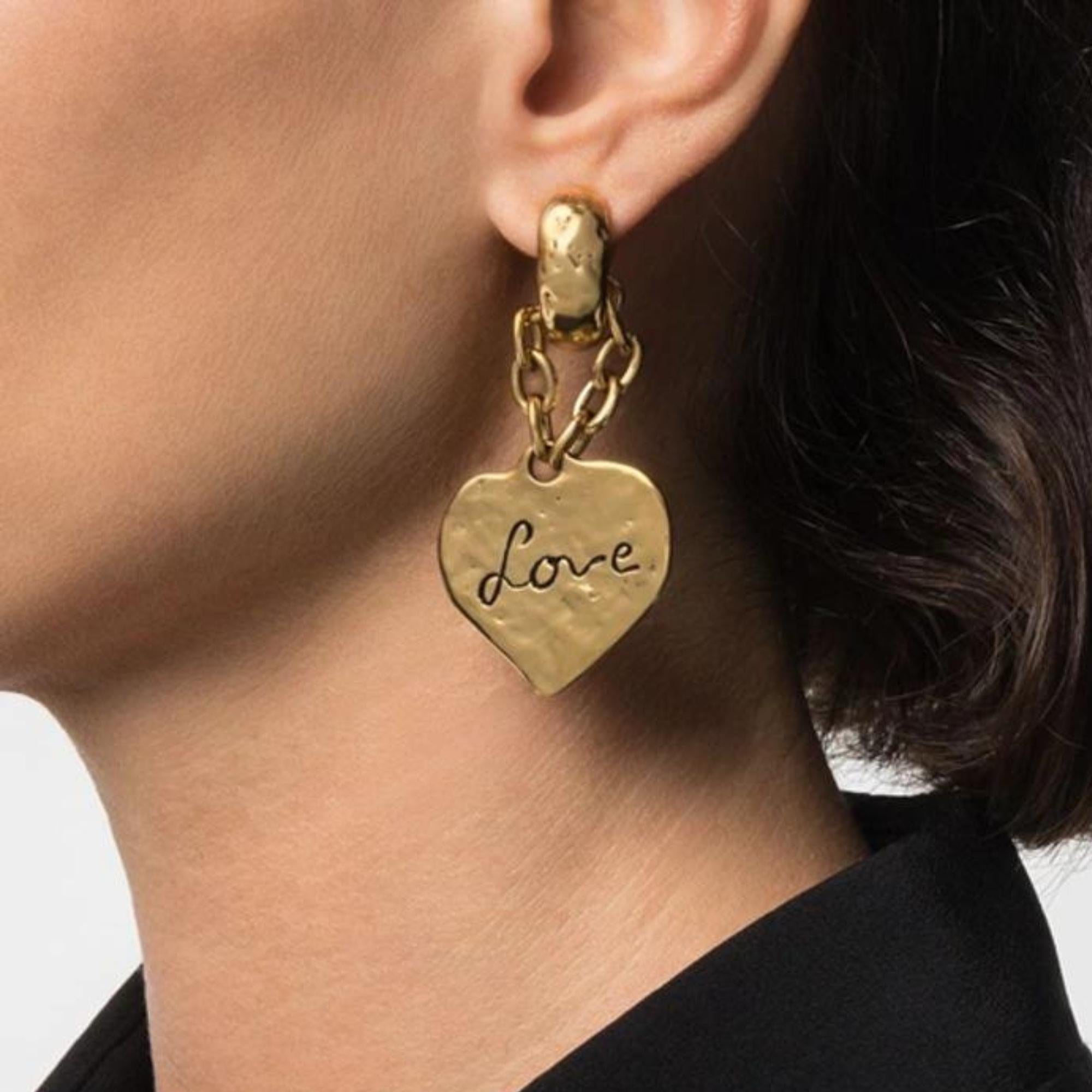 Gold-tone clip-on earrings from Saint Laurent. Made in metal with an antiqued gold finish and feature an embossed logo, a heart shape and “love