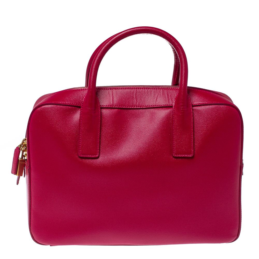 This Museum briefcase from Saint Laurent is impeccably crafted from grained leather and exhibits a lovely magenta pink hue. Styled with dual top handles that carry an attached clochette, its top zipper with a padlock opens to a fabric-lined spacious