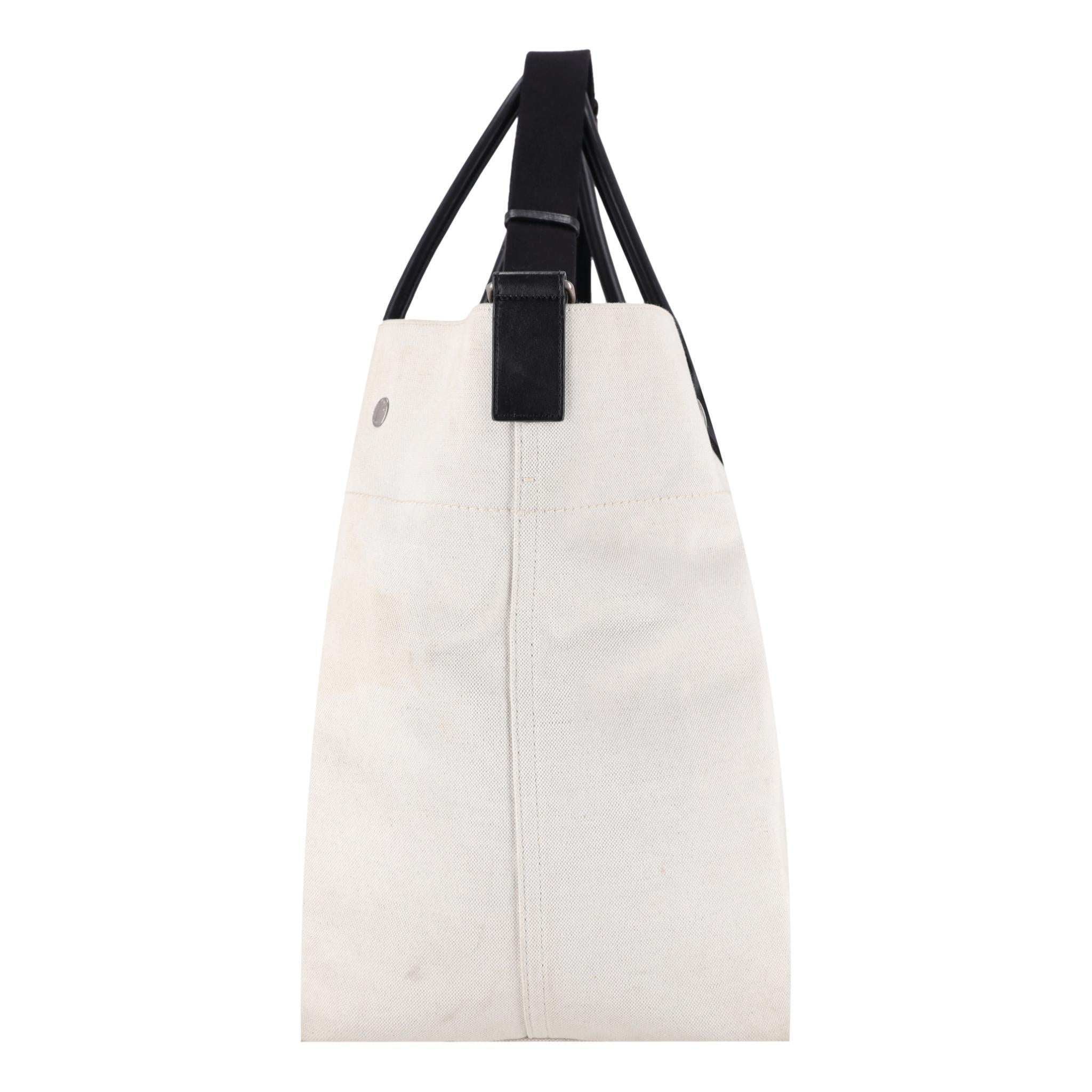 Saint Laurent Maxi Rive Gauche Canvas Tote Bag

Cream white canvas tote bag designed with contrasting black logo print to the front.

Featuring leather dual top handles and adjustable shoulder strap.

Detailed with silver, branded studs and snap