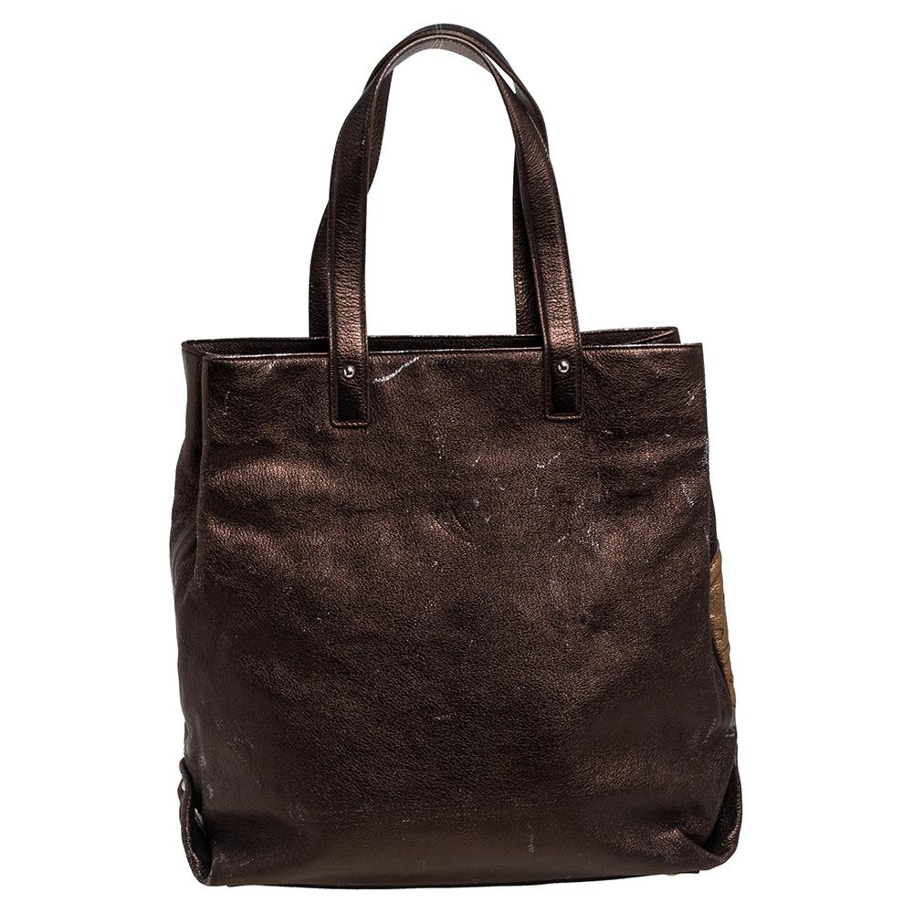 An absolute delight, this tote is a Saint Laurent creation! Crafted from leather, the bag features metallic brown and gold hues, dual handles, an embossed brand logo detailing on the front, and a canvas interior sized perfectly to hold your