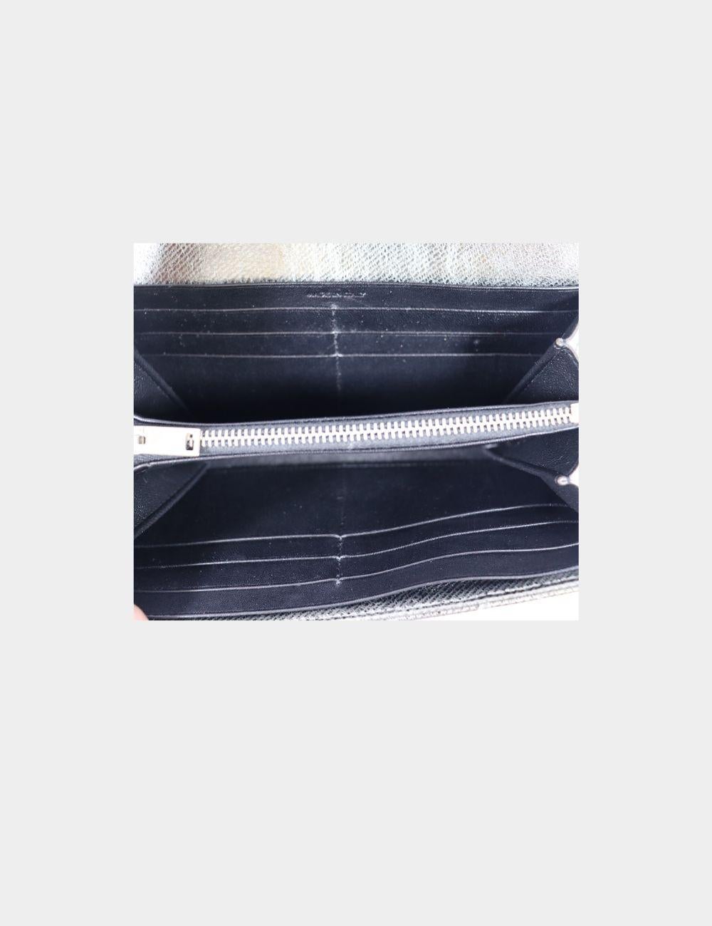 Cartera acolchada Chevron metalizada Saint Laurent, con logotipo en tono plateado, solapa frontal con cierre magnético y bolsillos interiores con cremallera y solapa.

Altura: 10,5 cm
Anchura: 19 cm
Profundidad: 3 cm
Estado general: Bueno
Estado