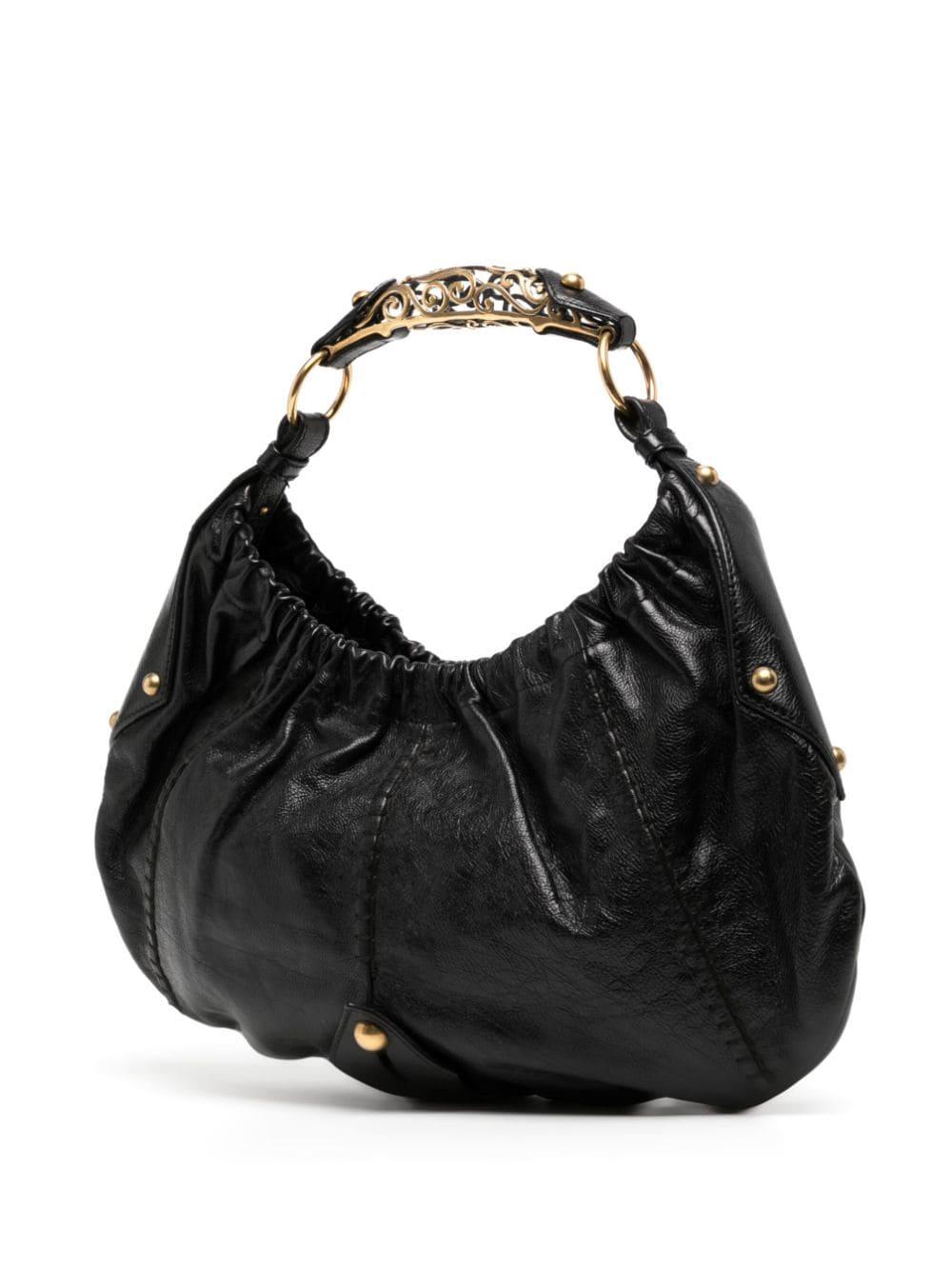 * Black calf leather
* Ruched detailing
* Gold-tone stud detailing & hardware
* Iconic Mombasa gold embellished top handle
* Magnetic fastening closure
* Satin interior
* Removable pouch
* Very good condition: minor signs of wear & scratches on
