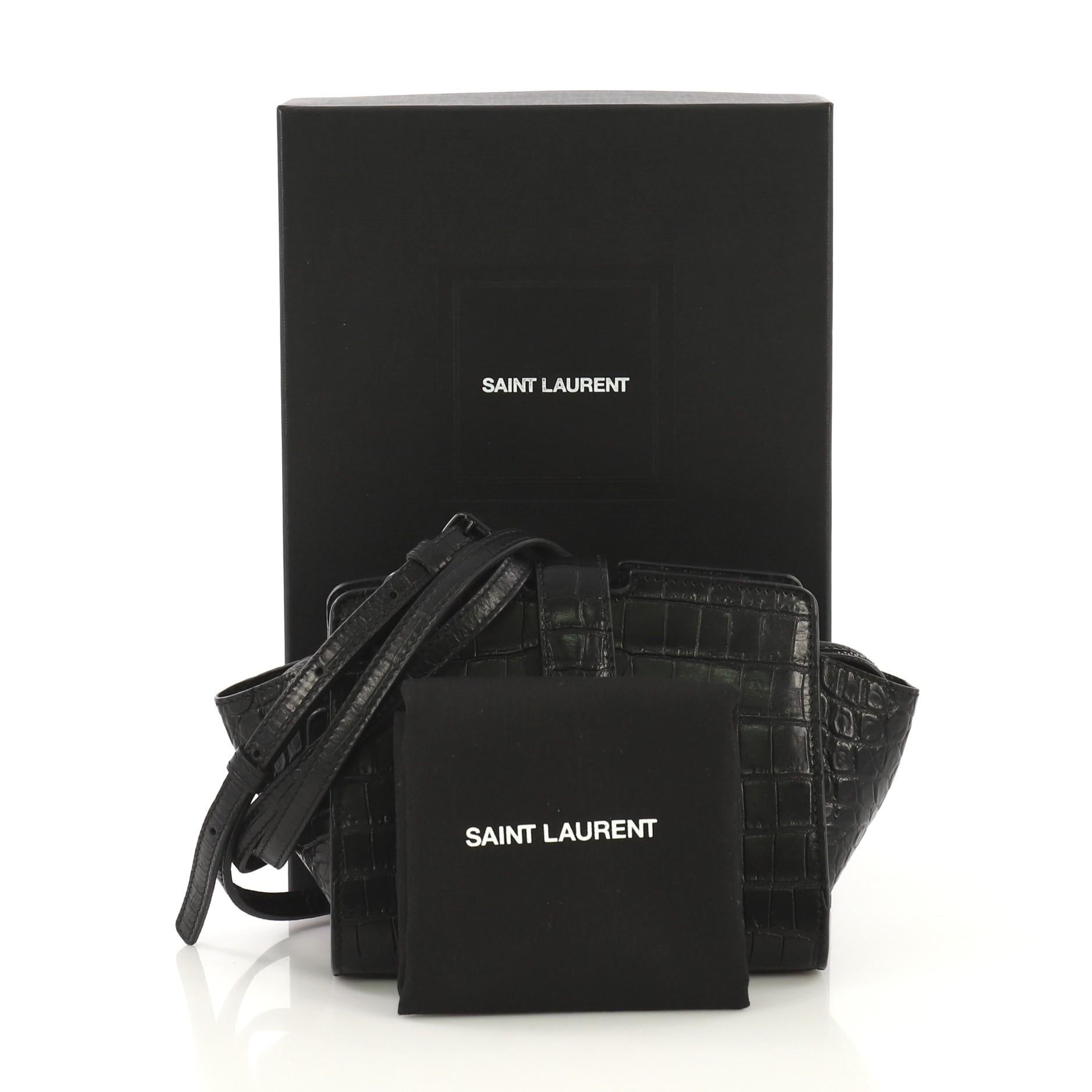 This Saint Laurent Monogram Cabas Crocodile Embossed Leather Toy, crafted from black crocodile embossed leather, features an adjustable shoulder strap, YSL metal logo at the front, and black-tone hardware. Its flap tab magnetic snap and zip closure