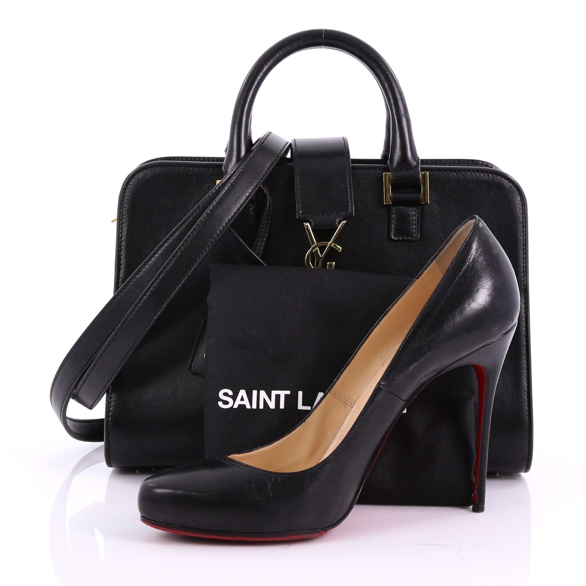 This Saint Laurent Monogram Cabas Downtown Leather Baby, crafted from black leather, features dual rolled handles, YSL metal logo at the front, protective base studs, and gold-tone hardware. Its magnetic snap and zip closure opens to a black leather