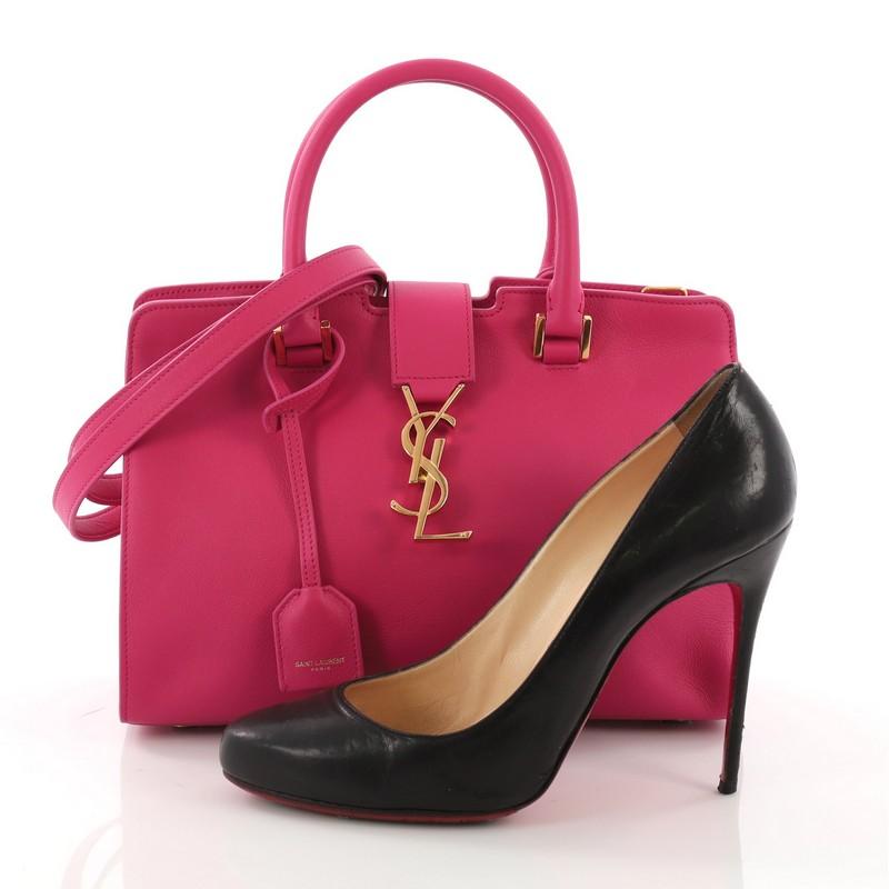 This Saint Laurent Monogram Cabas Downtown Leather Baby, crafted from pink leather, features dual rolled handles, YSL metal logo at the front, protective base studs, and gold-tone hardware. Its magnetic snap and zip closure opens to a pink suede