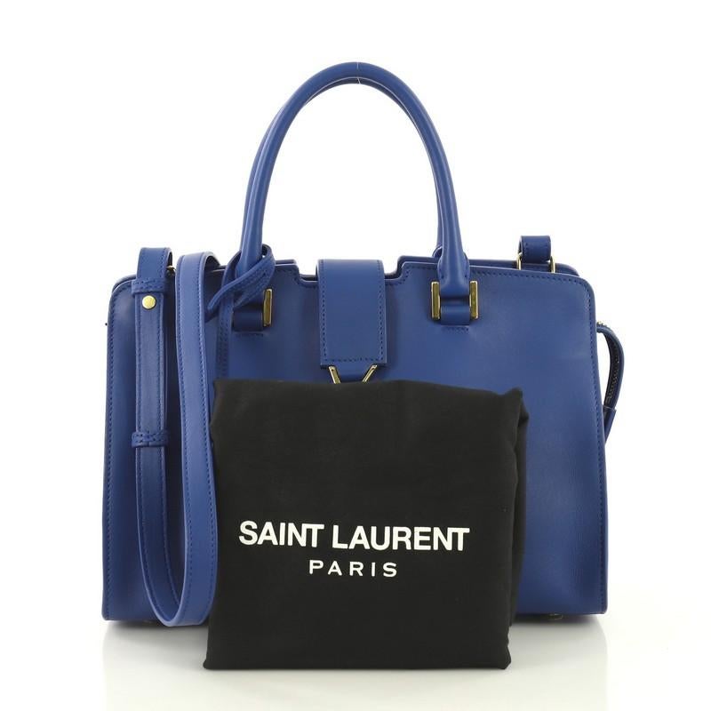 This Saint Laurent Monogram Cabas Leather Baby, crafted from blue leather, features dual rolled handles, YSL metal logo at the front, protective base studs, and gold-tone hardware. Its magnetic snap and zip closure opens to a blue suede interior